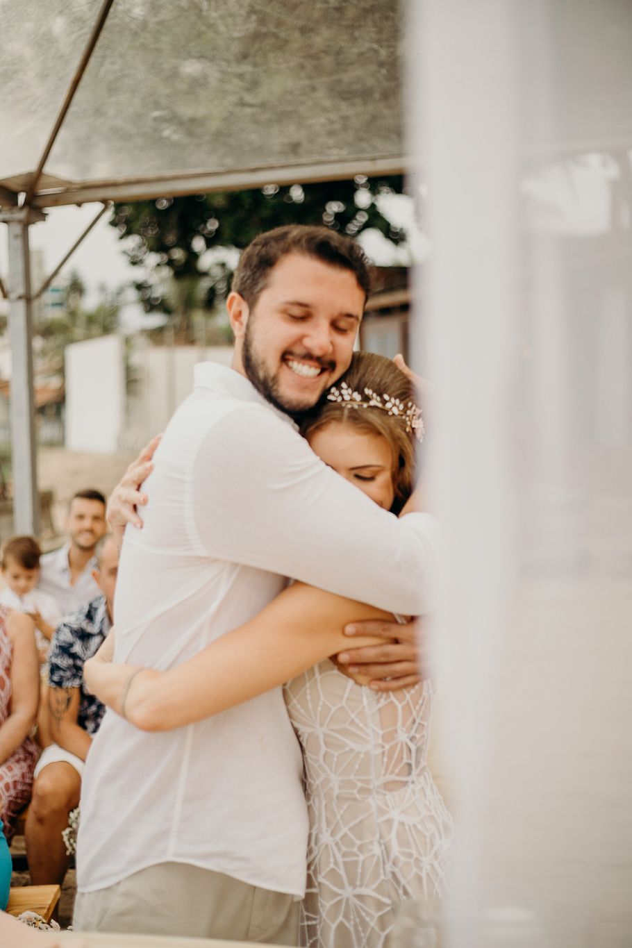 A joyful wedding celebration moment under a white tent with string lights.