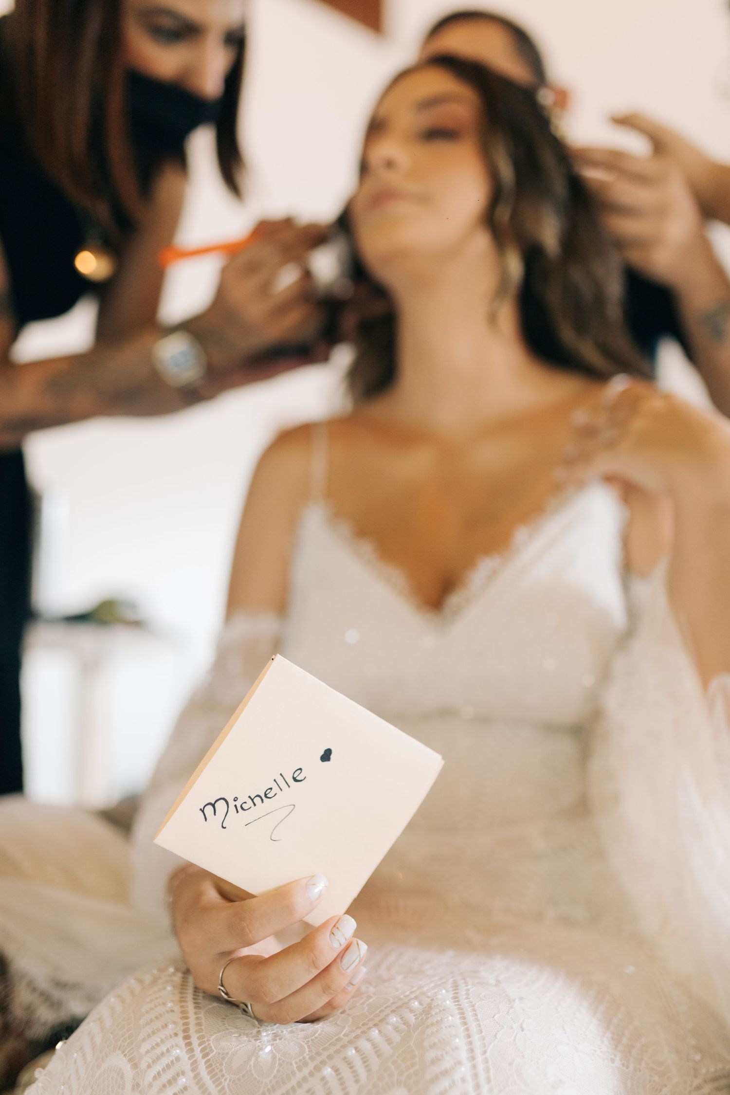 Final wedding preparations with makeup being applied while holding a personalized note.