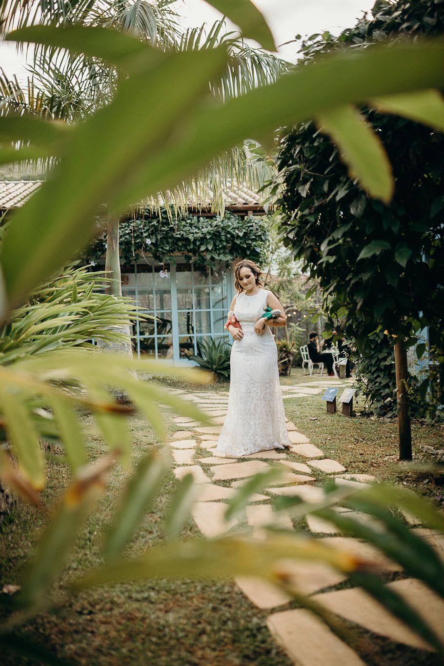 Garden pathway framed by tropical foliage and palm leaves.