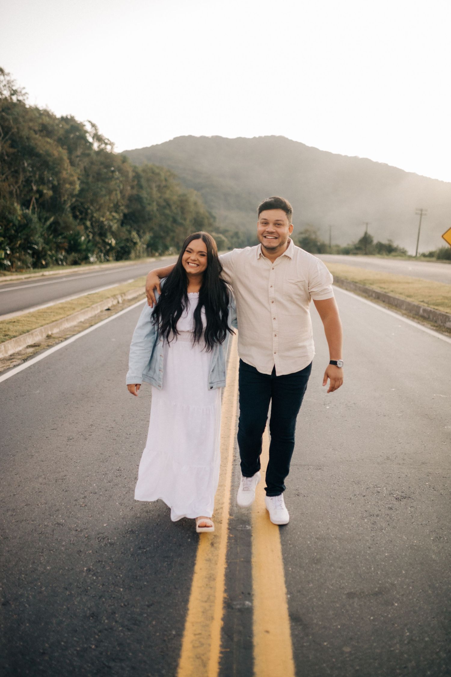 Happy couple playfully walking down a mountain road at dusk.