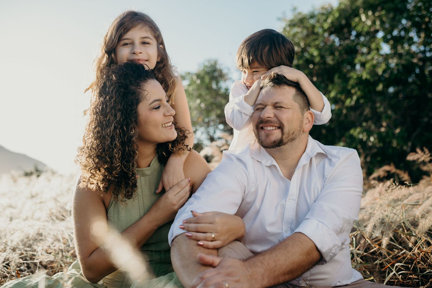 A romantic couple embraces while sitting together in golden afternoon sunlight.