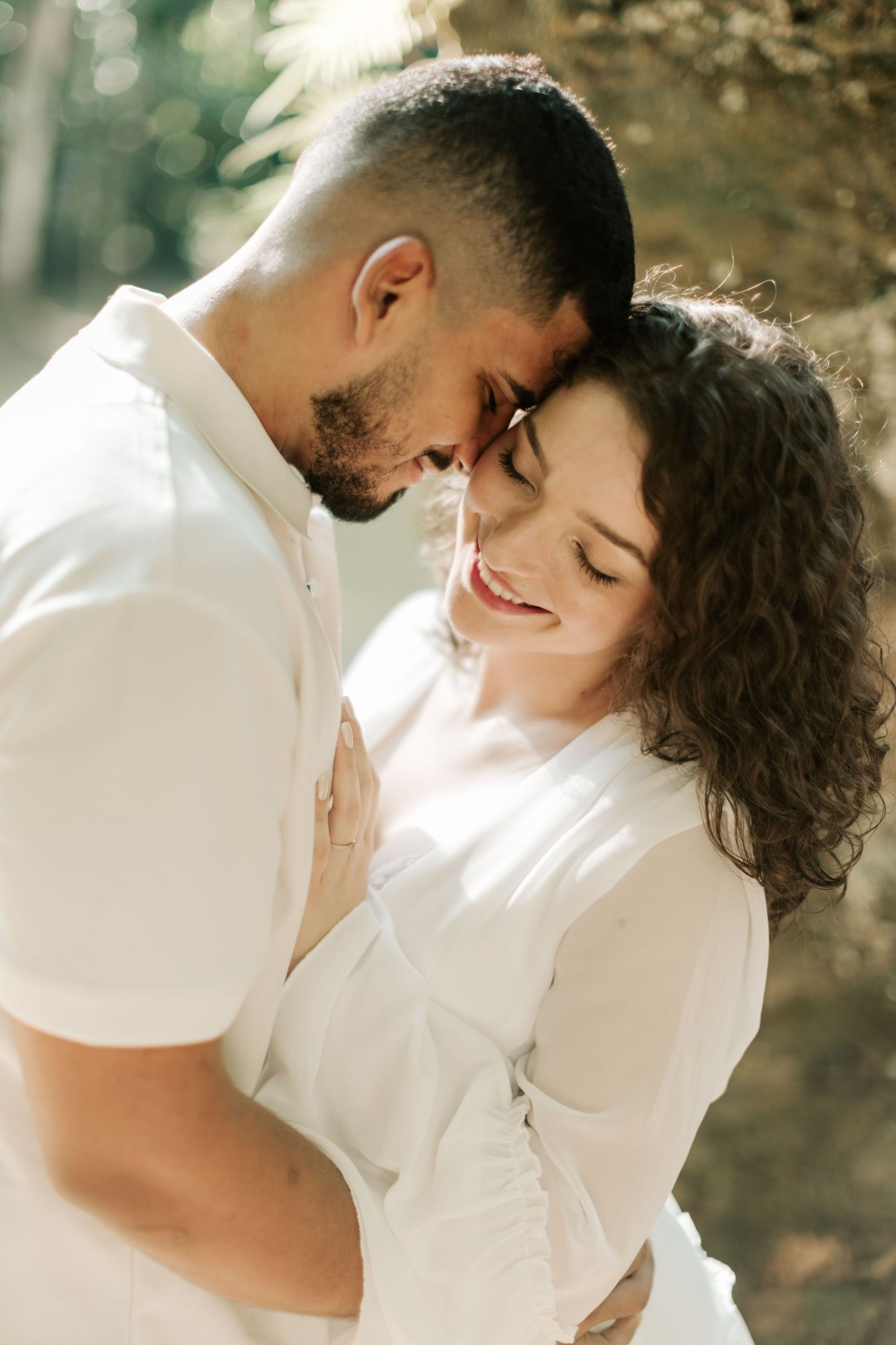 A tender moment between a couple in white clothing sharing an intimate embrace.