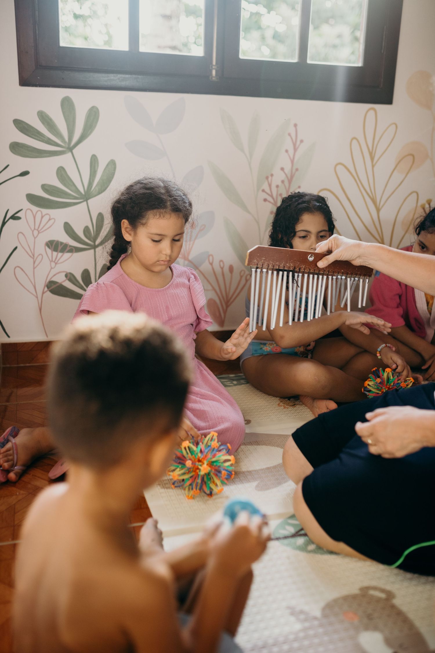 Music activity session with kalimba and instruments in room with botanical wall art.