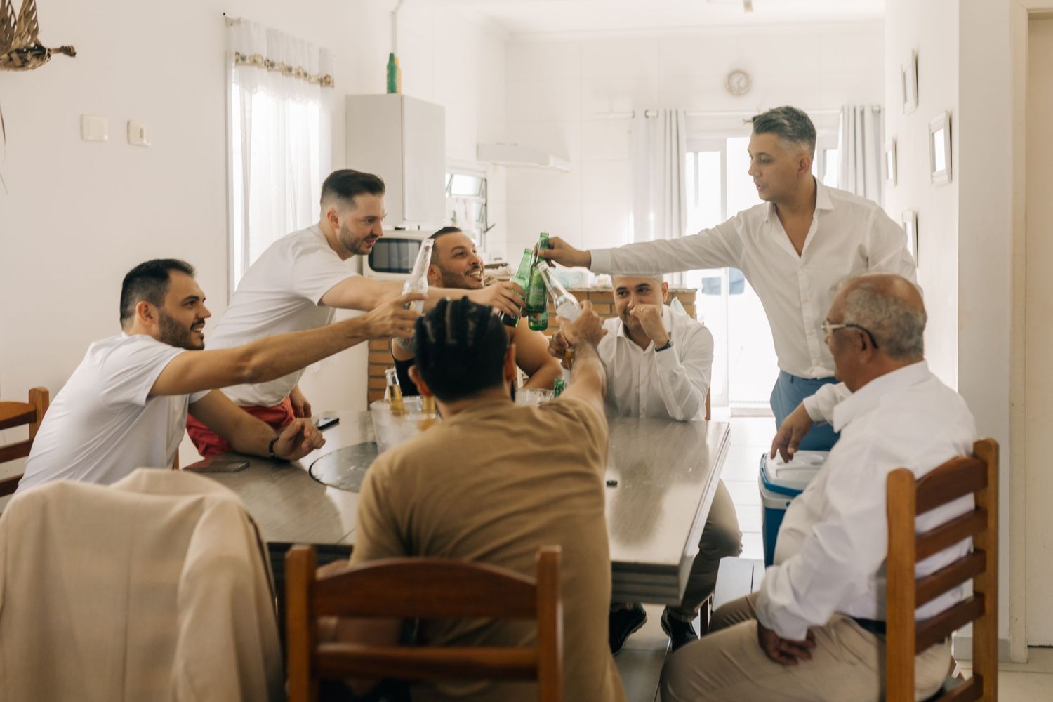 Group of friends toasting and celebrating with drinks around a dining table.