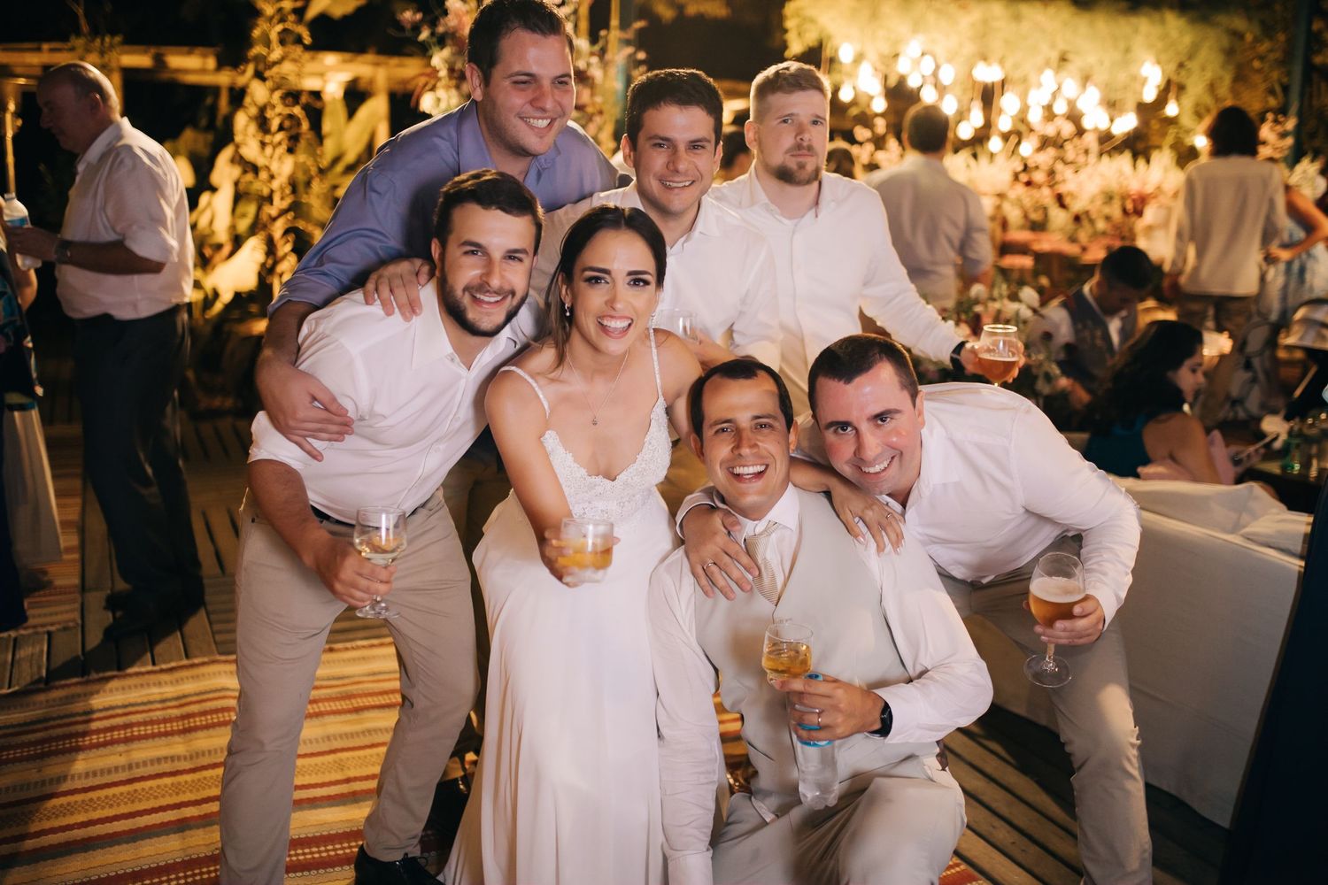 Friends celebrating together at a wedding reception with glowing decorative lights in background.