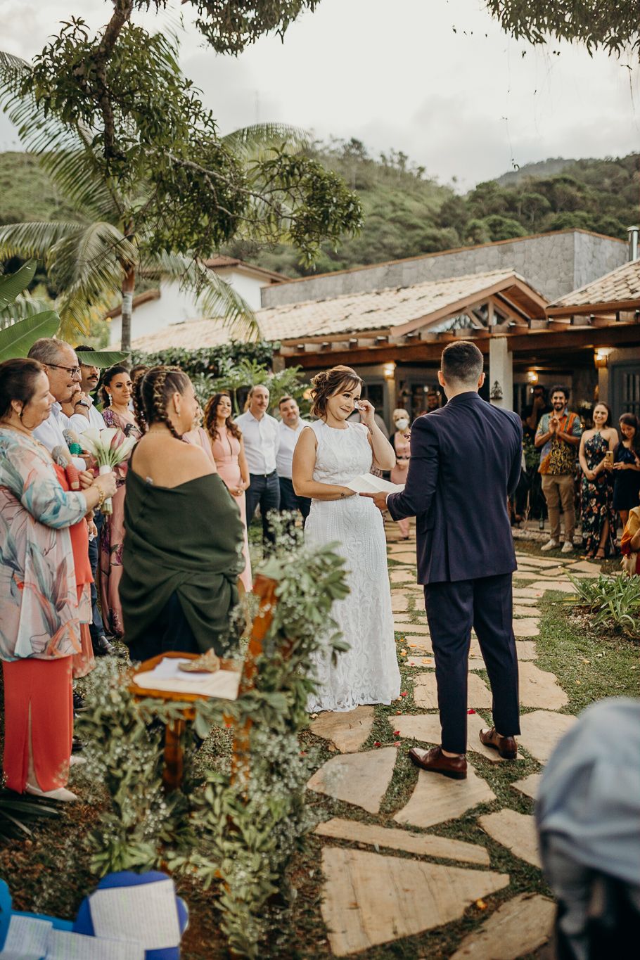 A wedding ceremony takes place at a rustic venue with mountain views and palm trees.