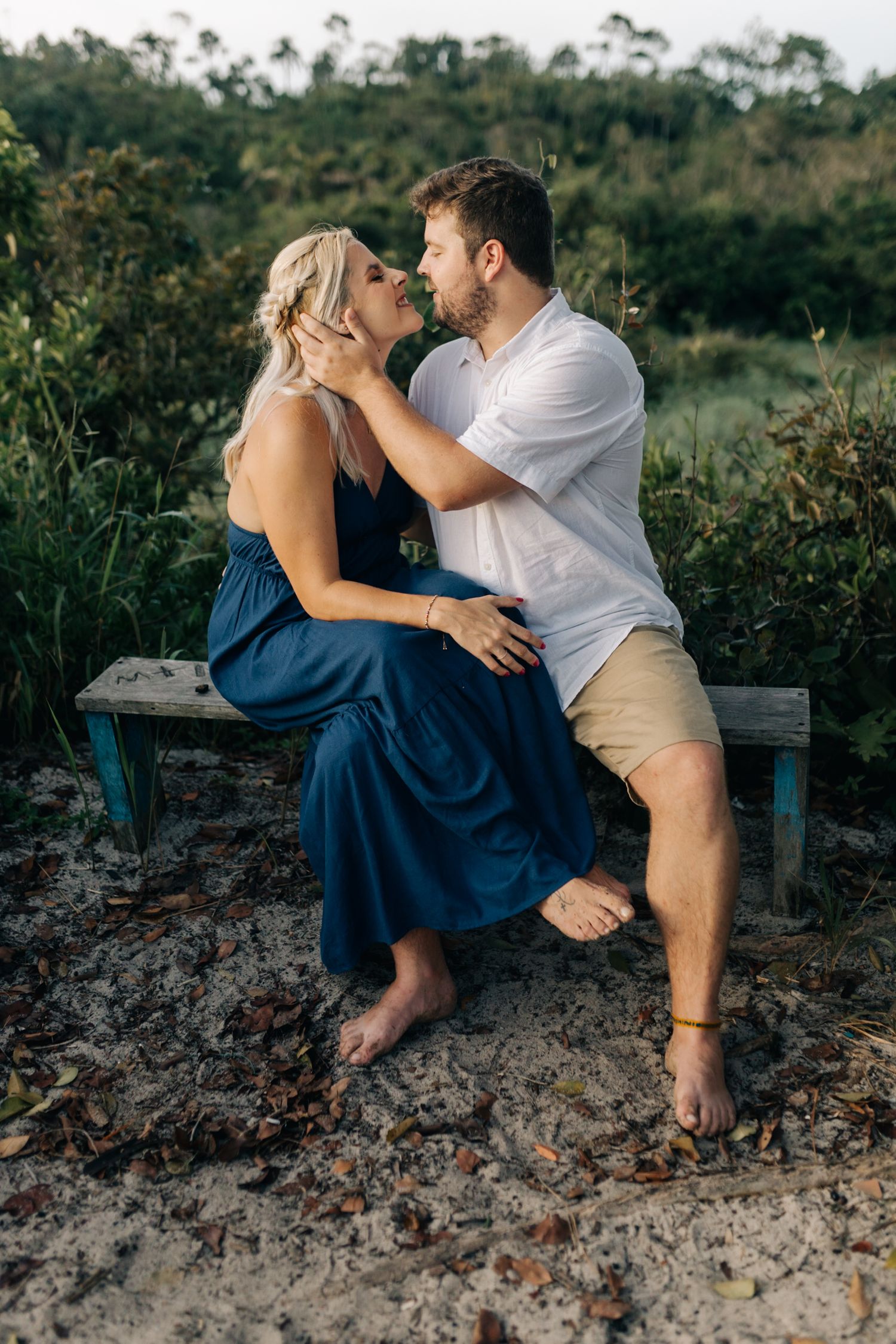 Romantic couple embracing on rocky terrain with natural landscape behind them.