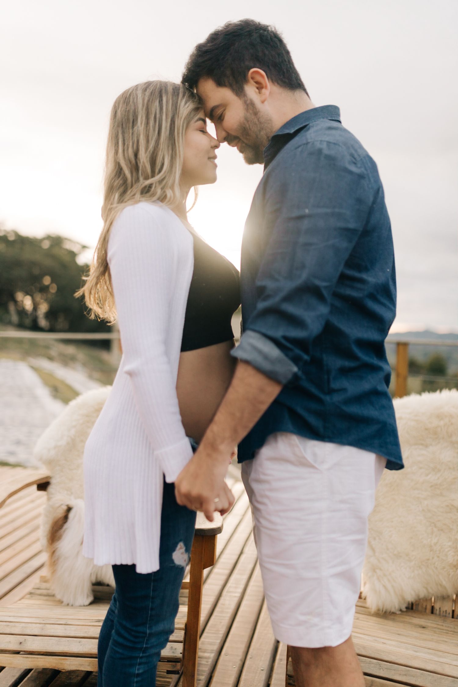 A romantic sunset moment between a couple standing on a wooden deck.