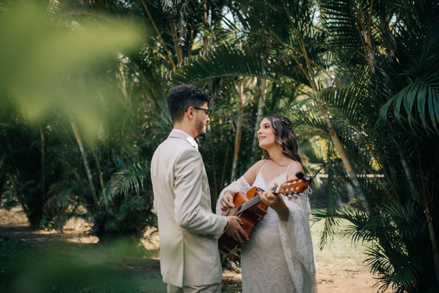 Couple with acoustic guitar surrounded by tropical garden at their wedding.