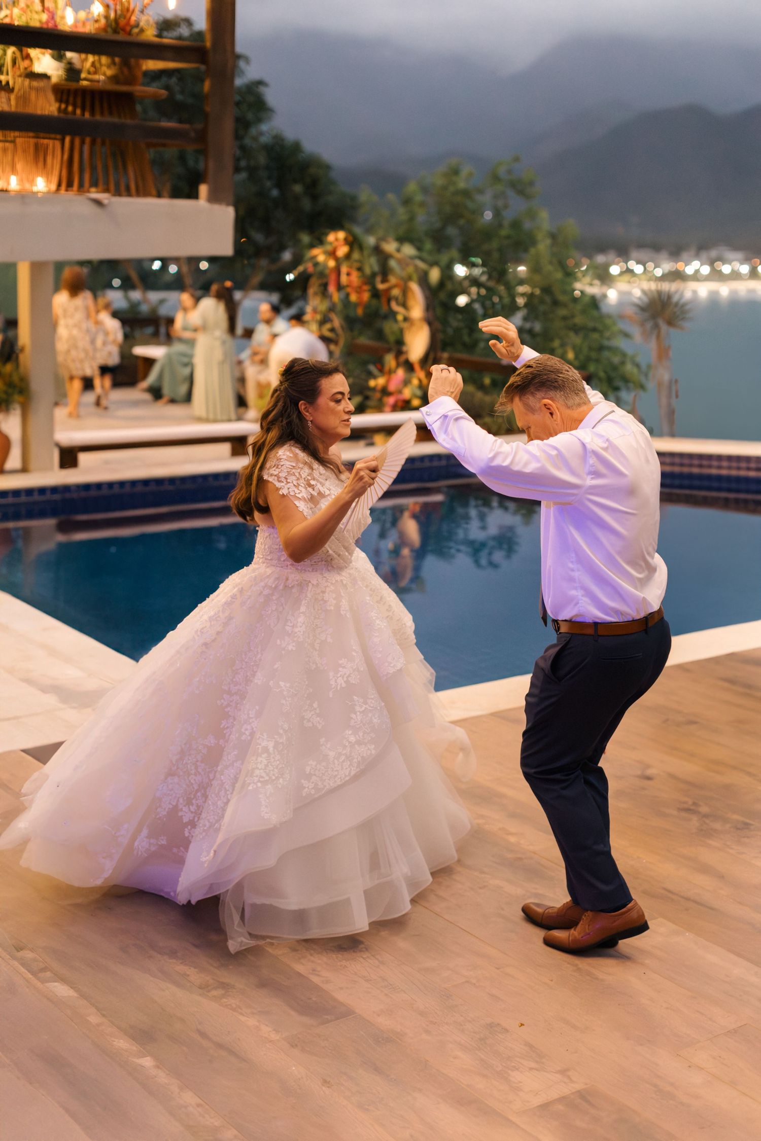 Couple dancing on outdoor patio with dramatic dip pose at sunset by pool.