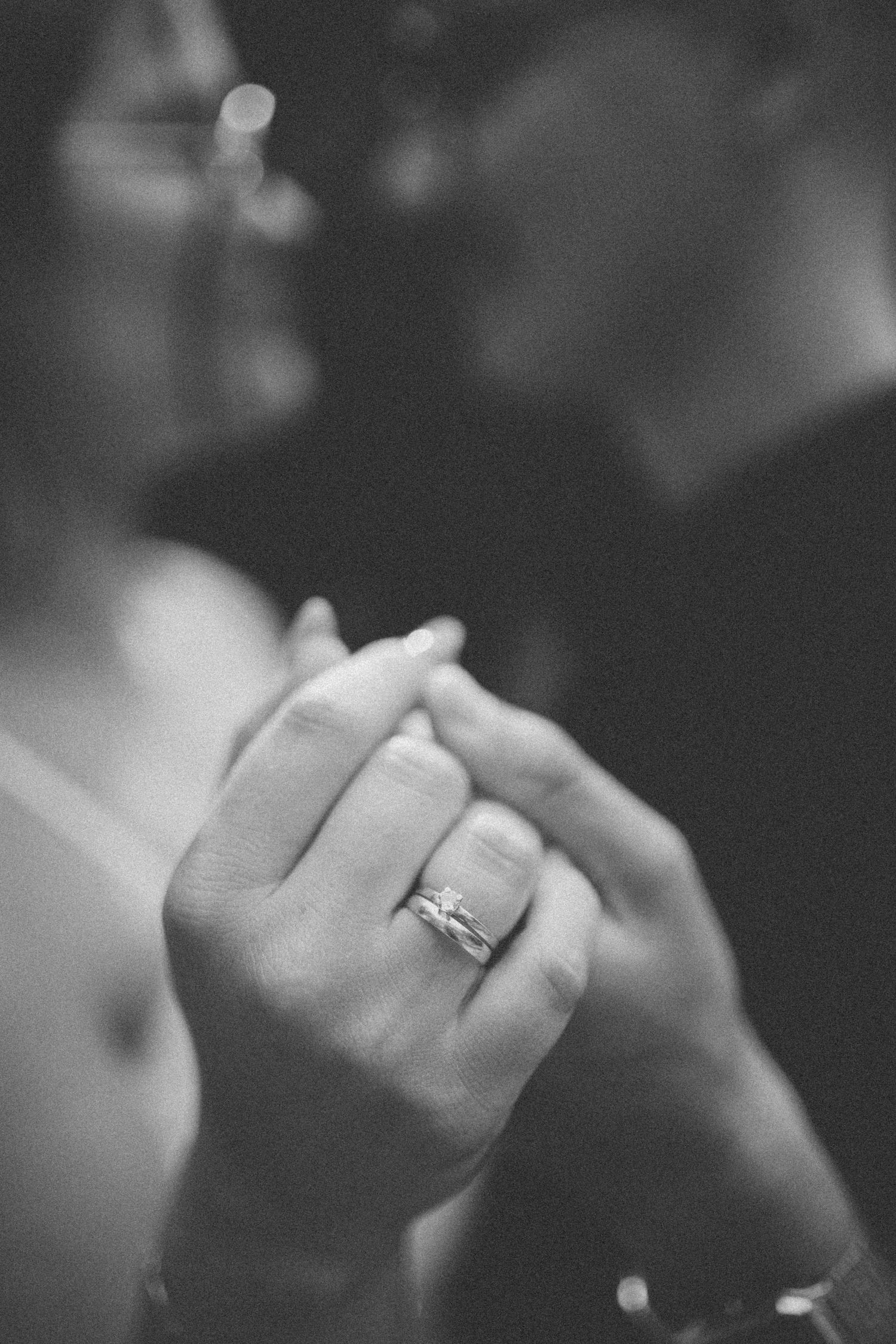 Close-up black and white photo of hands with an engagement ring.