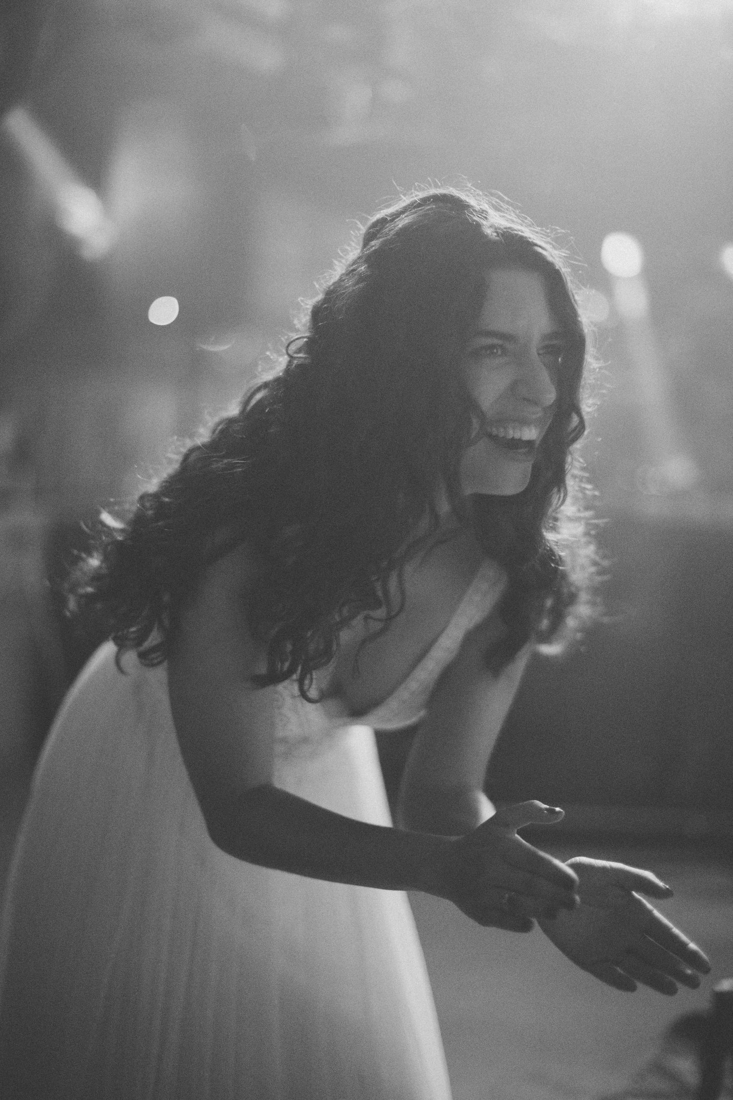 A silhouetted figure in a wedding dress illuminated by dramatic backlighting during the reception.