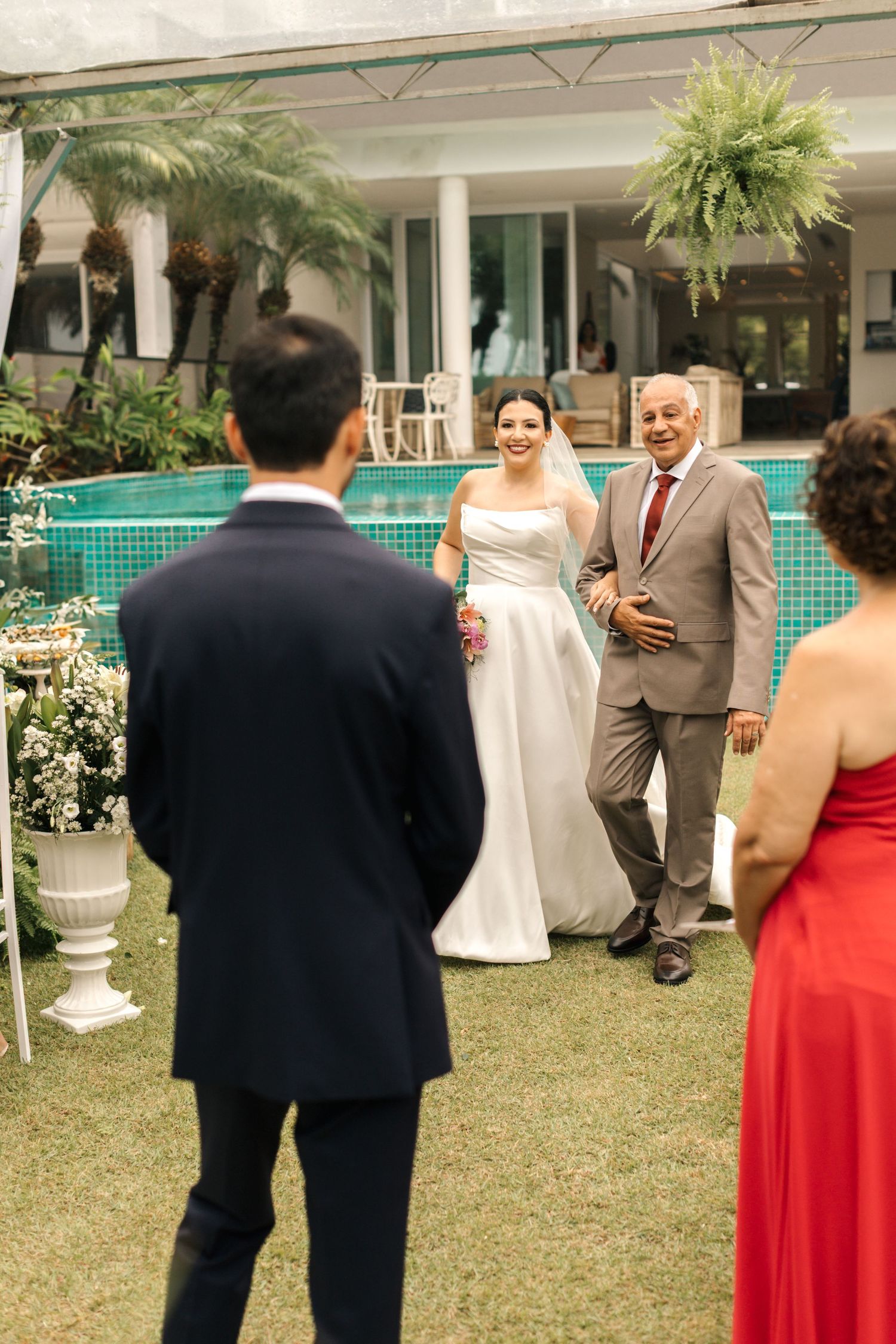Wedding celebration on a lawn with formal attire and architectural backdrop.