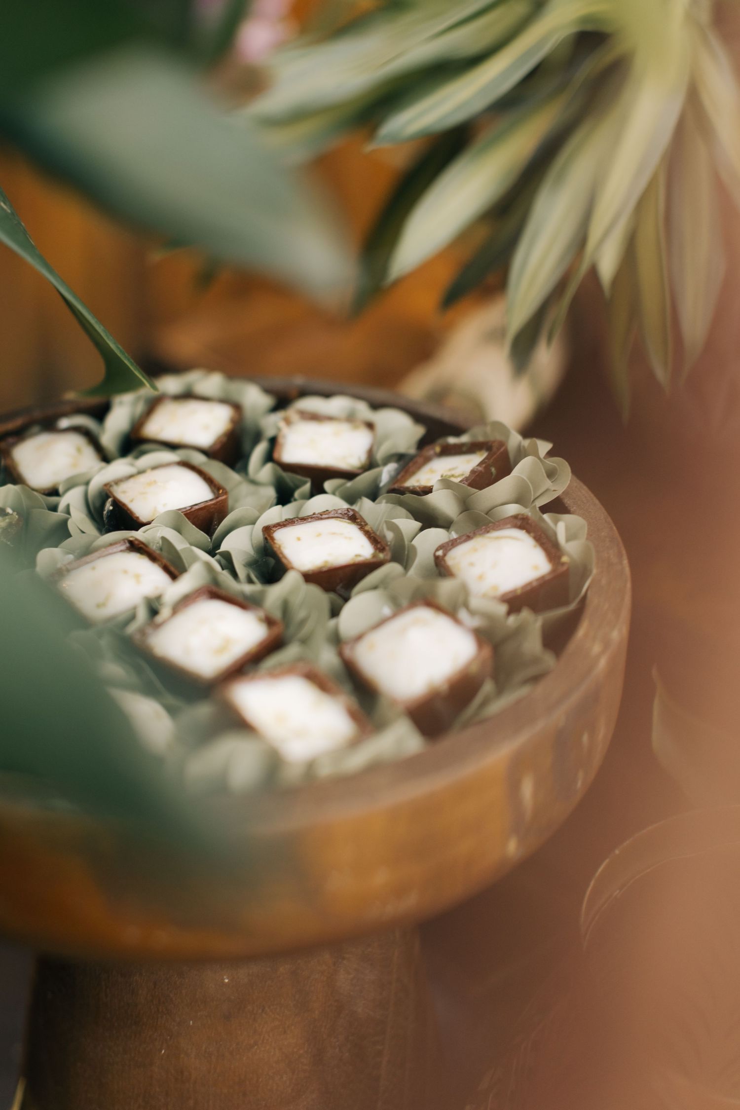 Artfully arranged white desserts in copper serving dish with tropical leaves.