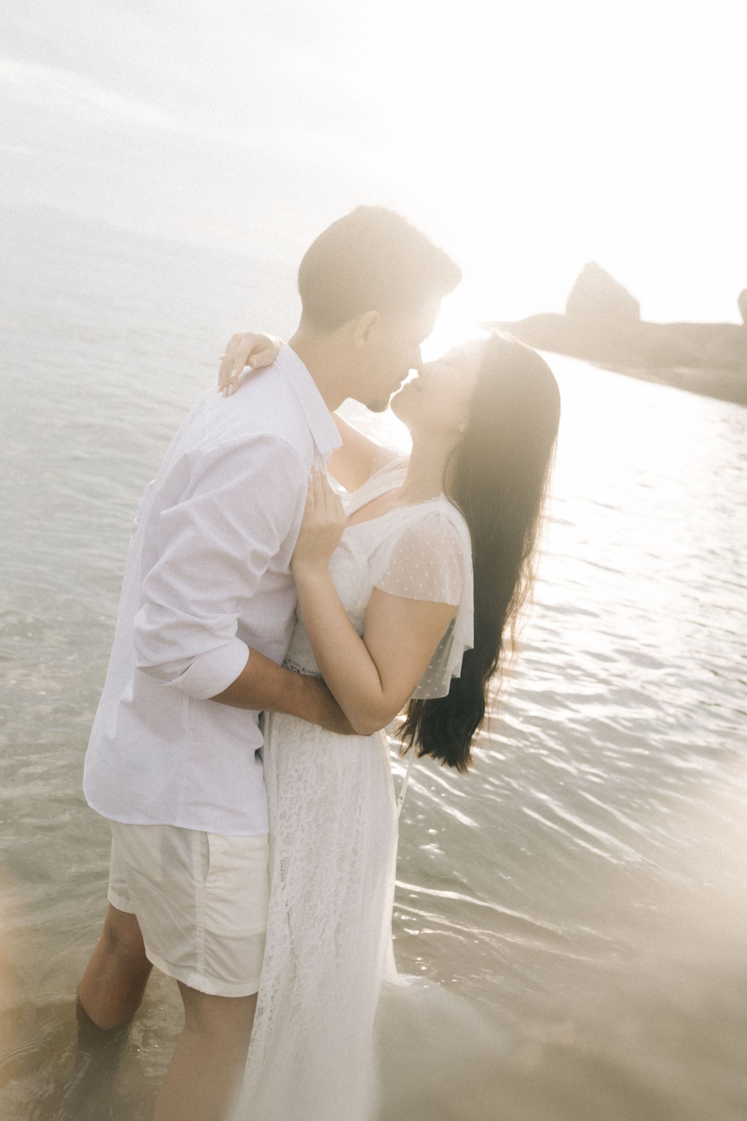 Dreamy seaside photoshoot with couple in coordinated white outfits.