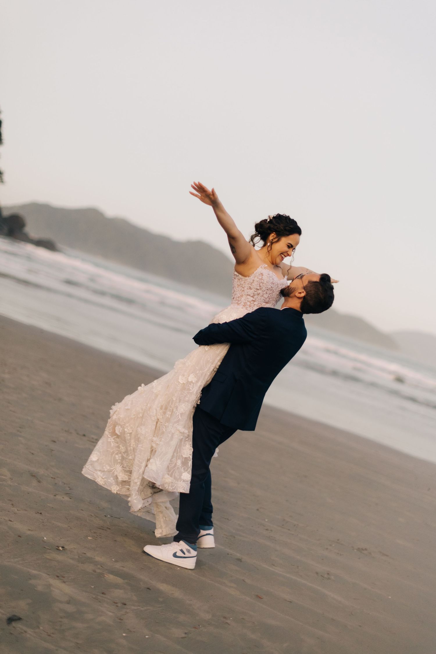 A joyful lift on the beach during a wedding photoshoot.