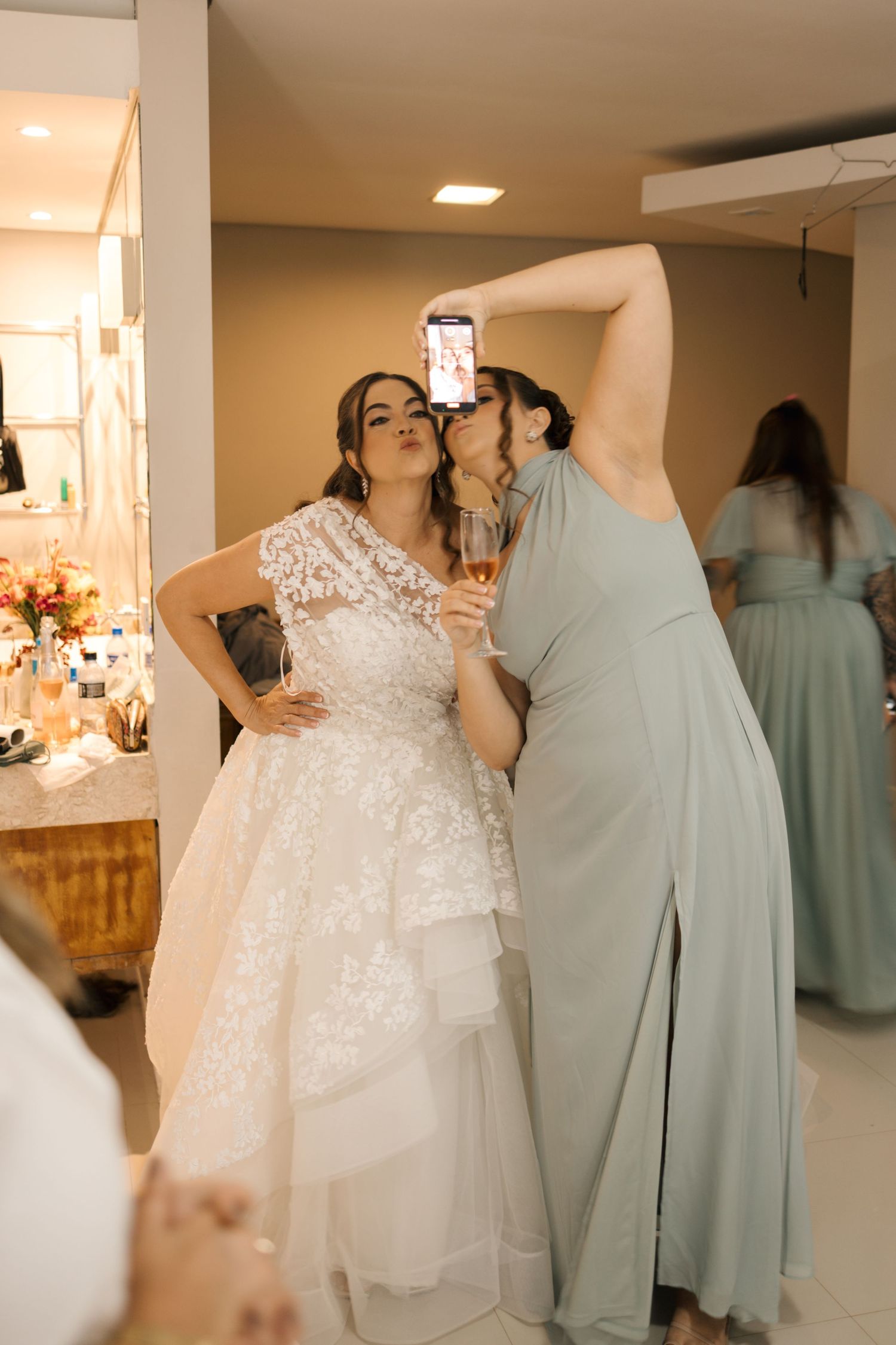 Bridesmaids in soft mint dresses gather around a bride wearing a flowing white wedding gown.