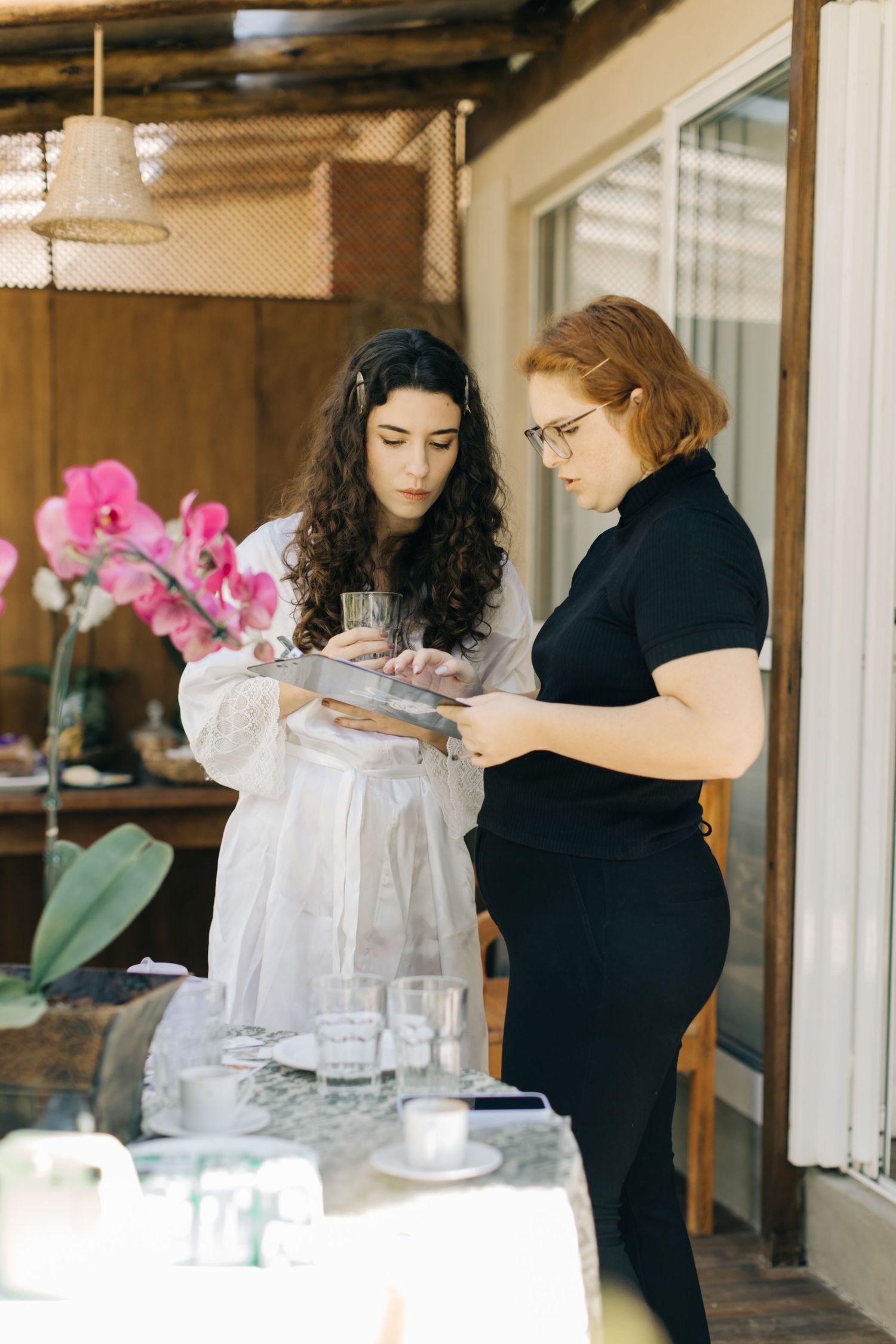 Salon professionals in black attire prepare for client services near orchid decorations.