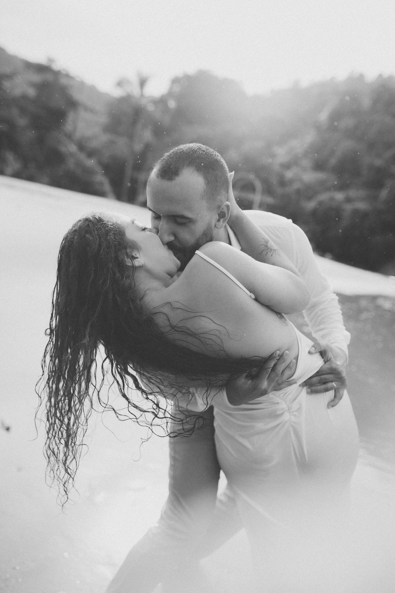 Black and white photo of a couple sharing a romantic dance pose on the beach.
