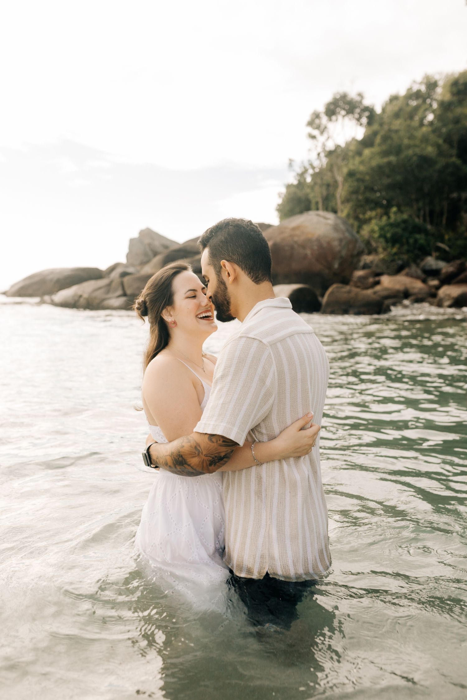Two people share an intimate moment while wading in crystal clear ocean waters.