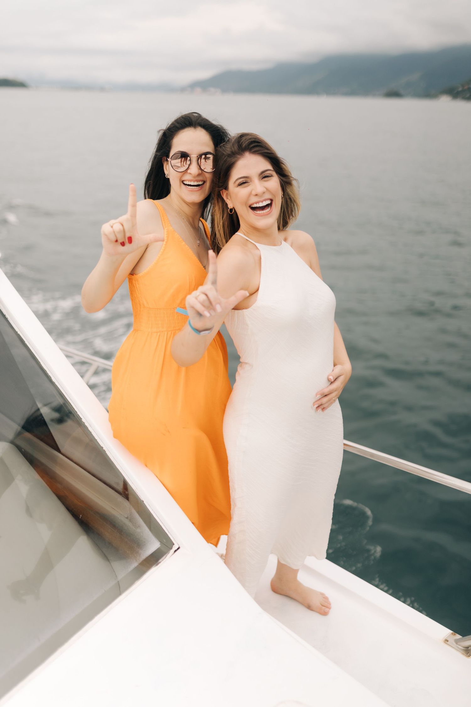Two friends laughing together while enjoying a boat ride on a cloudy day at sea.
