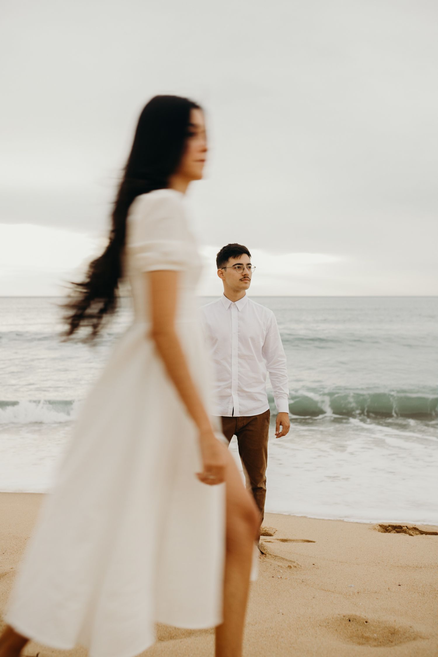 An artistic beach portrait with selective focus on figures in white and brown attire.