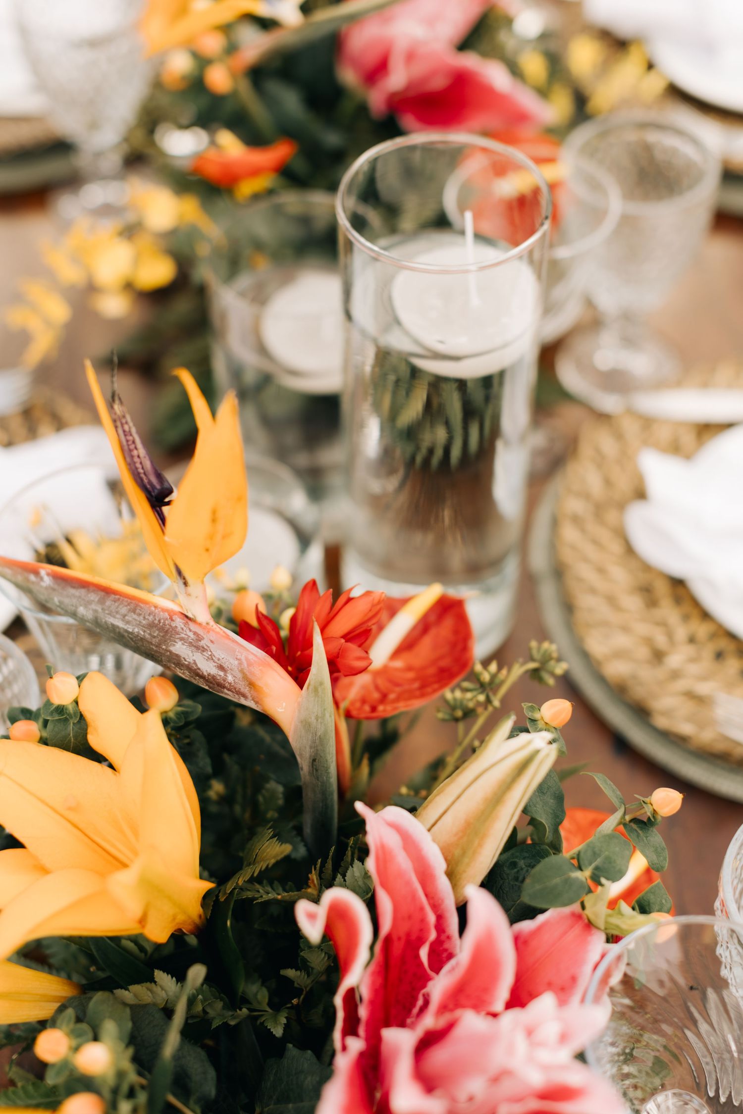 Vibrant tropical flower centerpiece with orange and pink lilies on an elegant table setting.