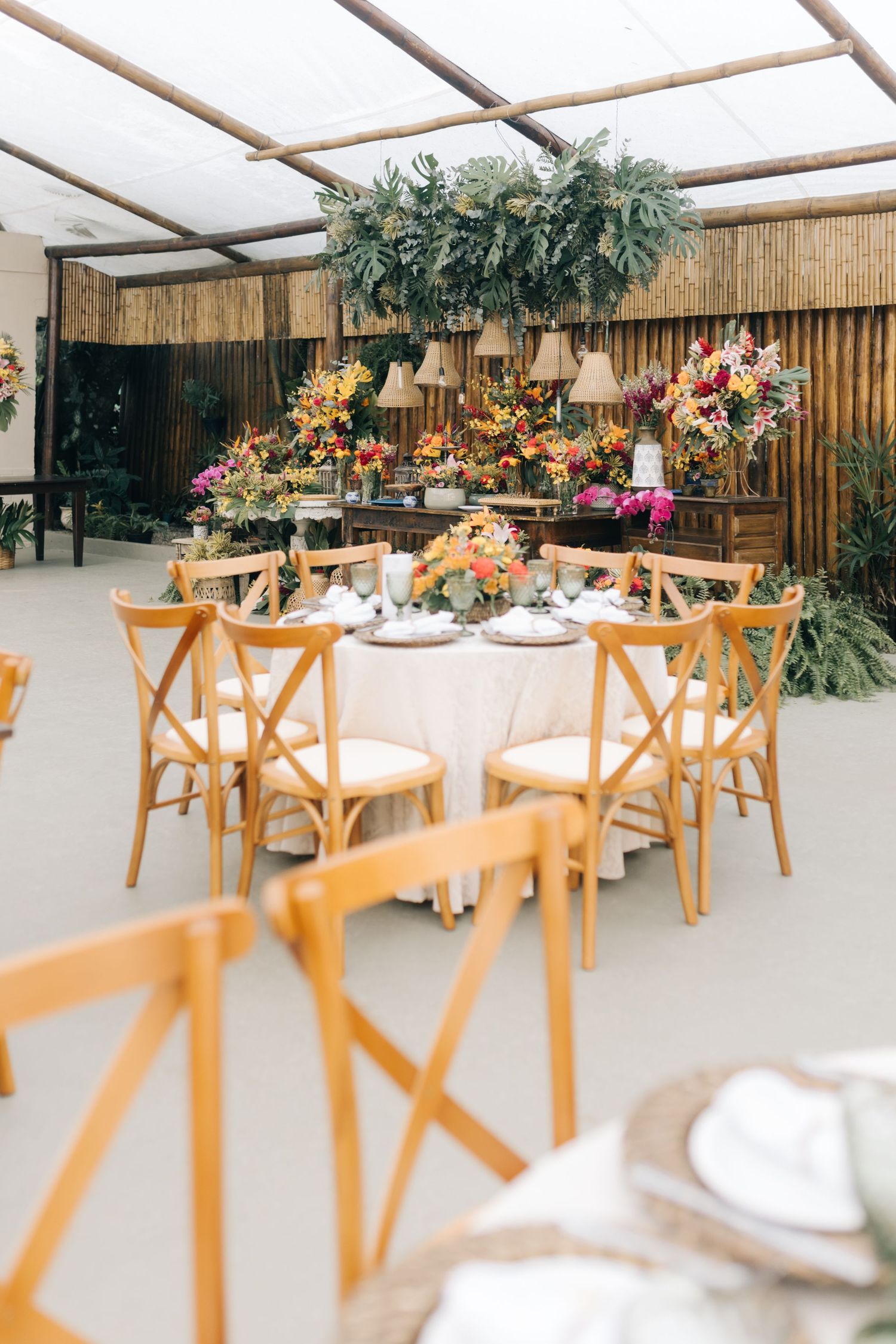 Modern wedding reception space with wooden crossback chairs and bamboo ceiling details.