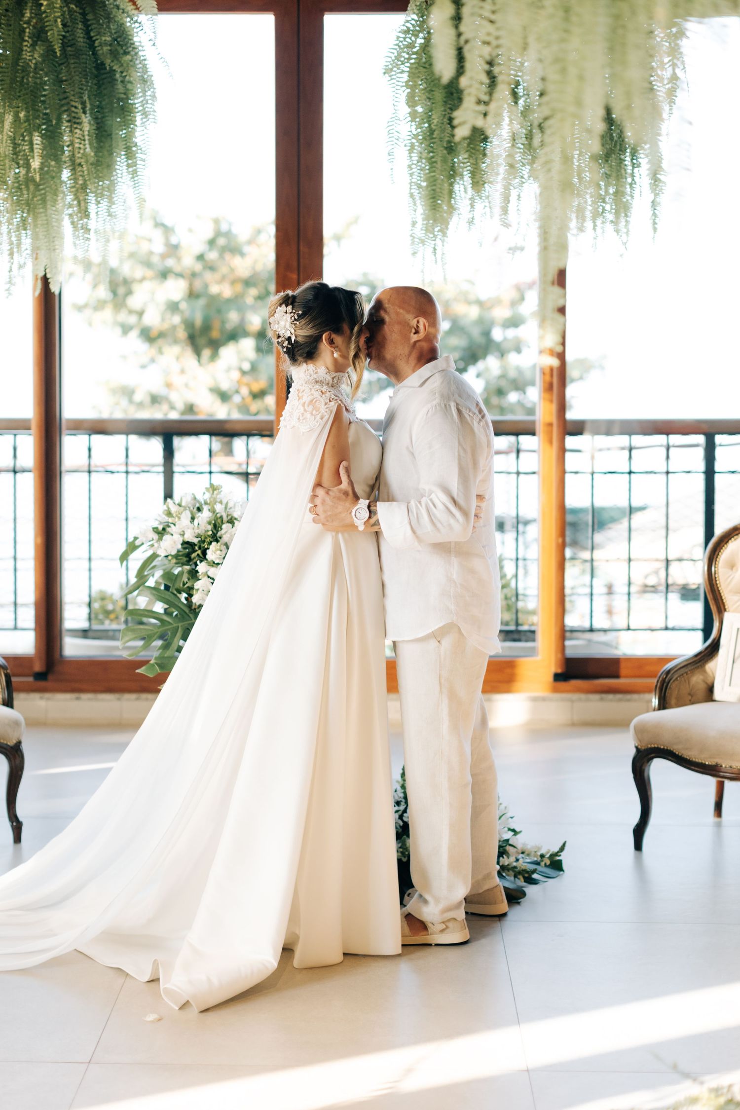 A romantic moment between newlyweds under hanging ferns during their wedding ceremony.