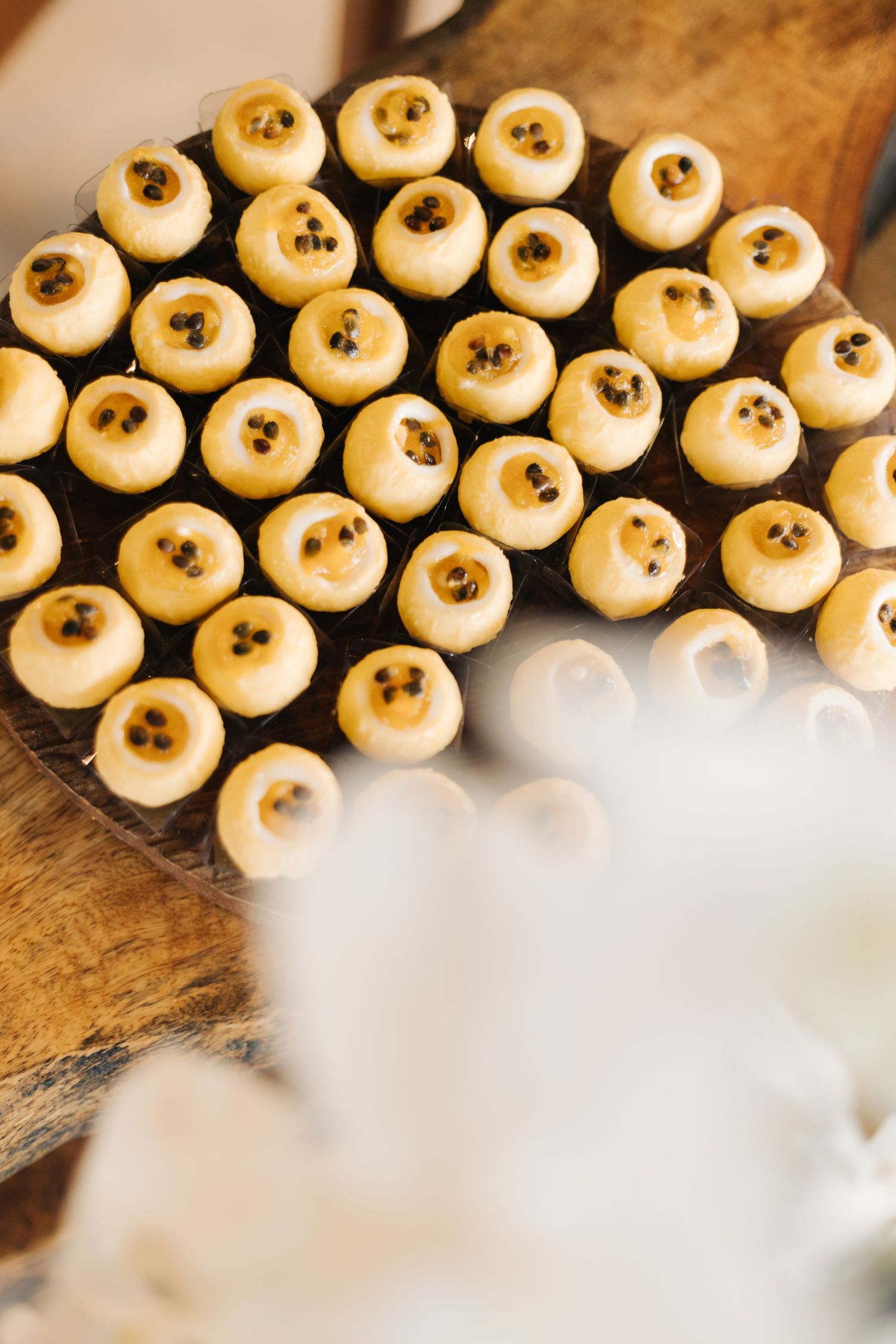 Rows of decorative white cake pops with gold accents arranged on a dark surface.