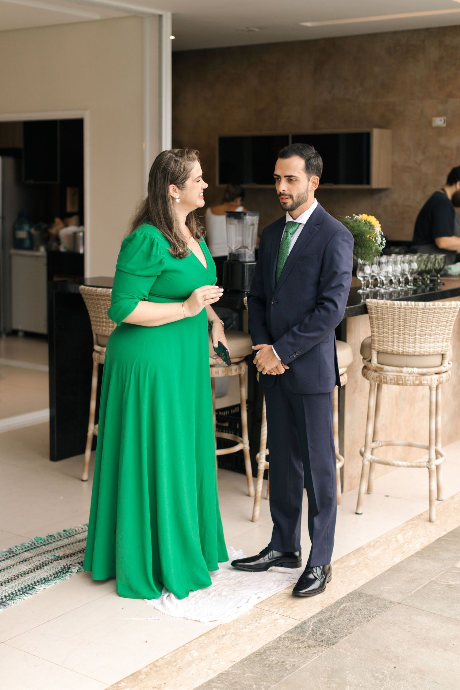 Formal event scene with guests in coordinating green attire chatting at reception area.