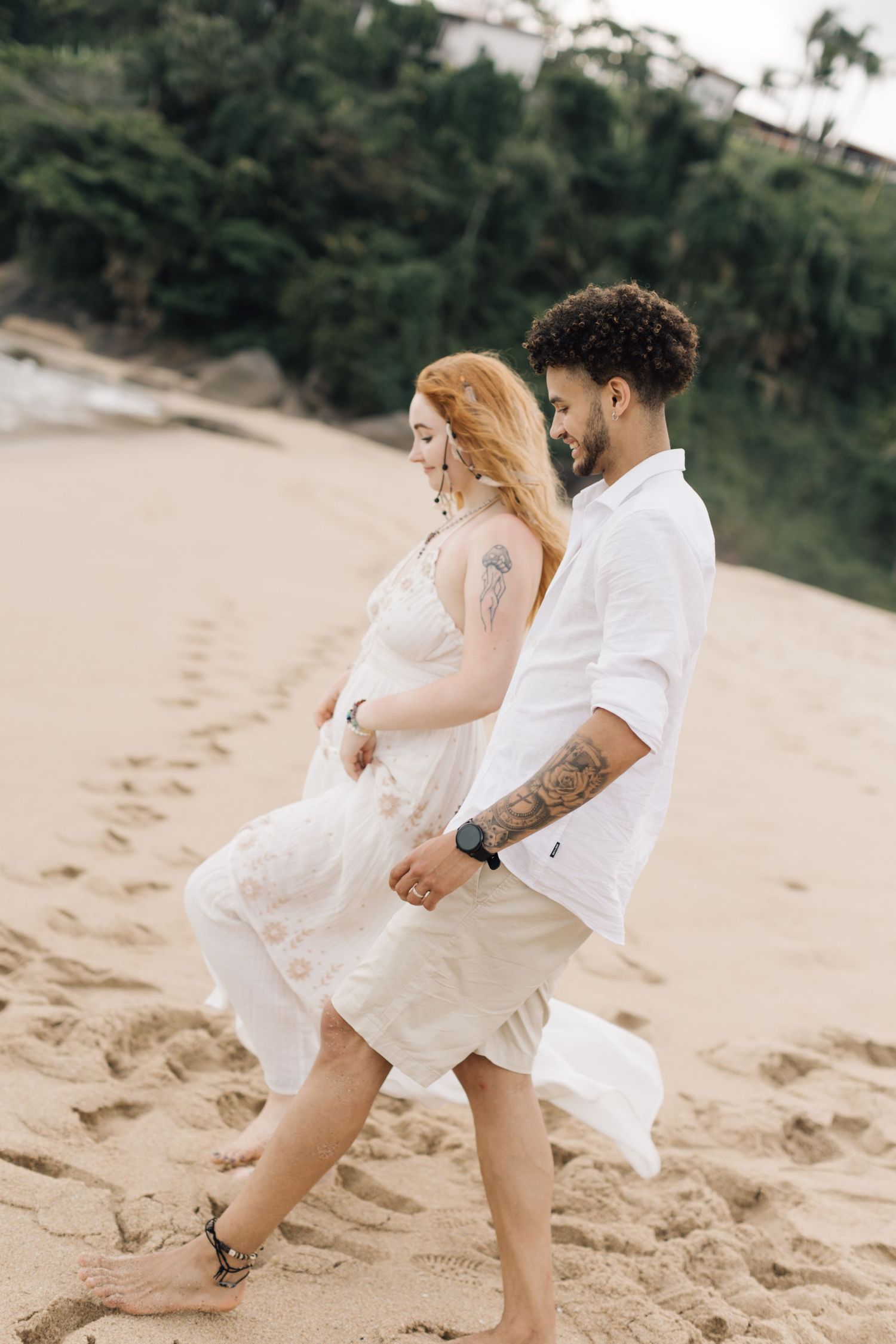 A couple in light summer clothing runs playfully along a scenic beach.