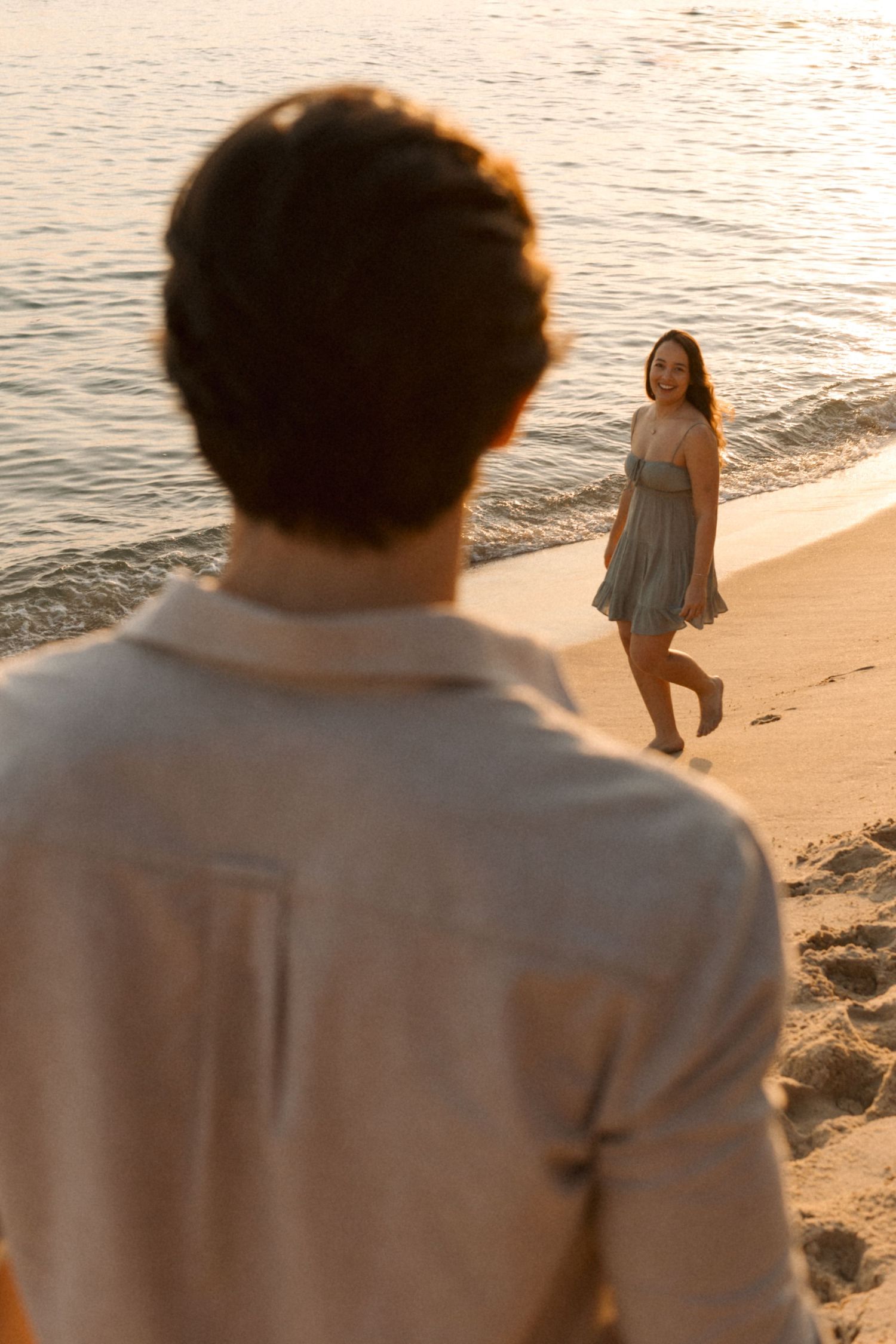 Two people sharing a romantic moment on a beach at golden hour.