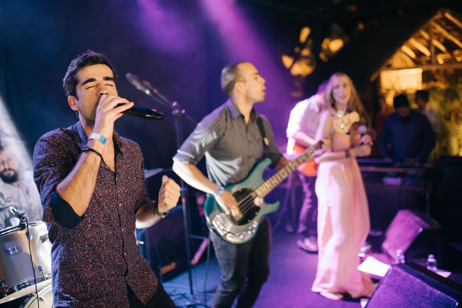 Band performing live music with purple stage lighting and musicians playing instruments.