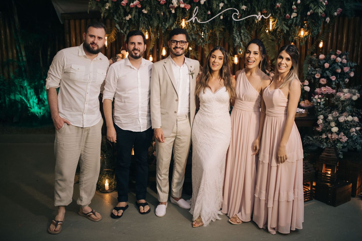 Wedding party poses in coordinated neutral tones during evening reception.