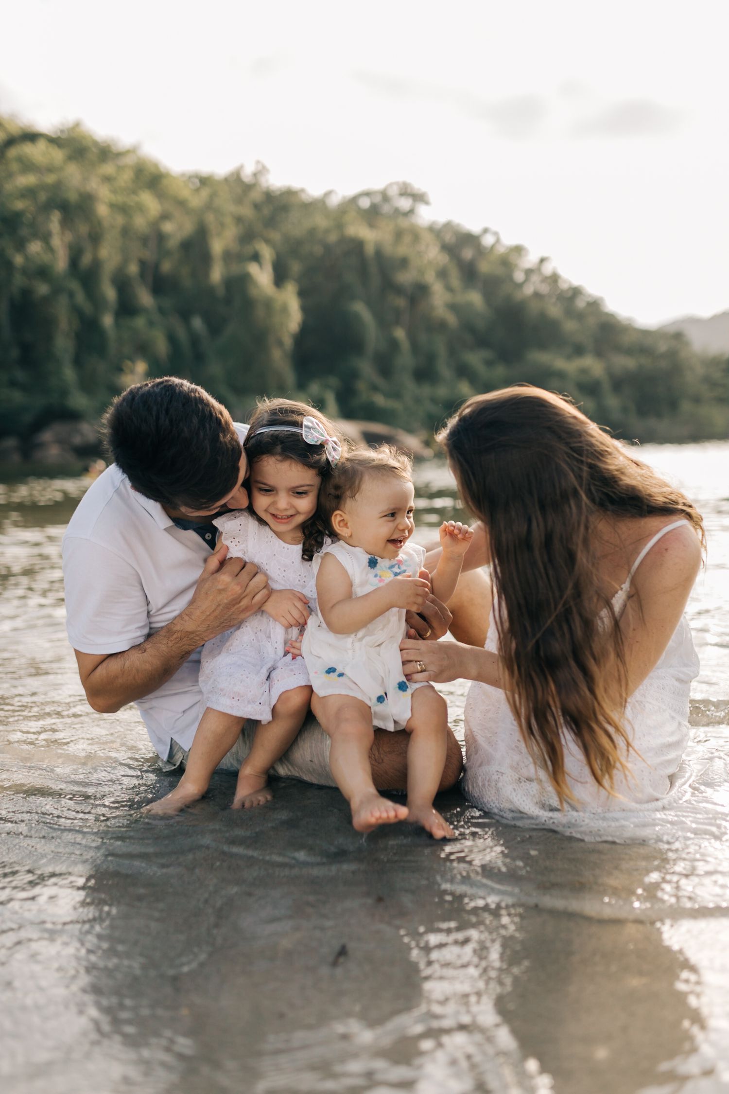 An intimate family moment shared at the water's edge during golden hour.
