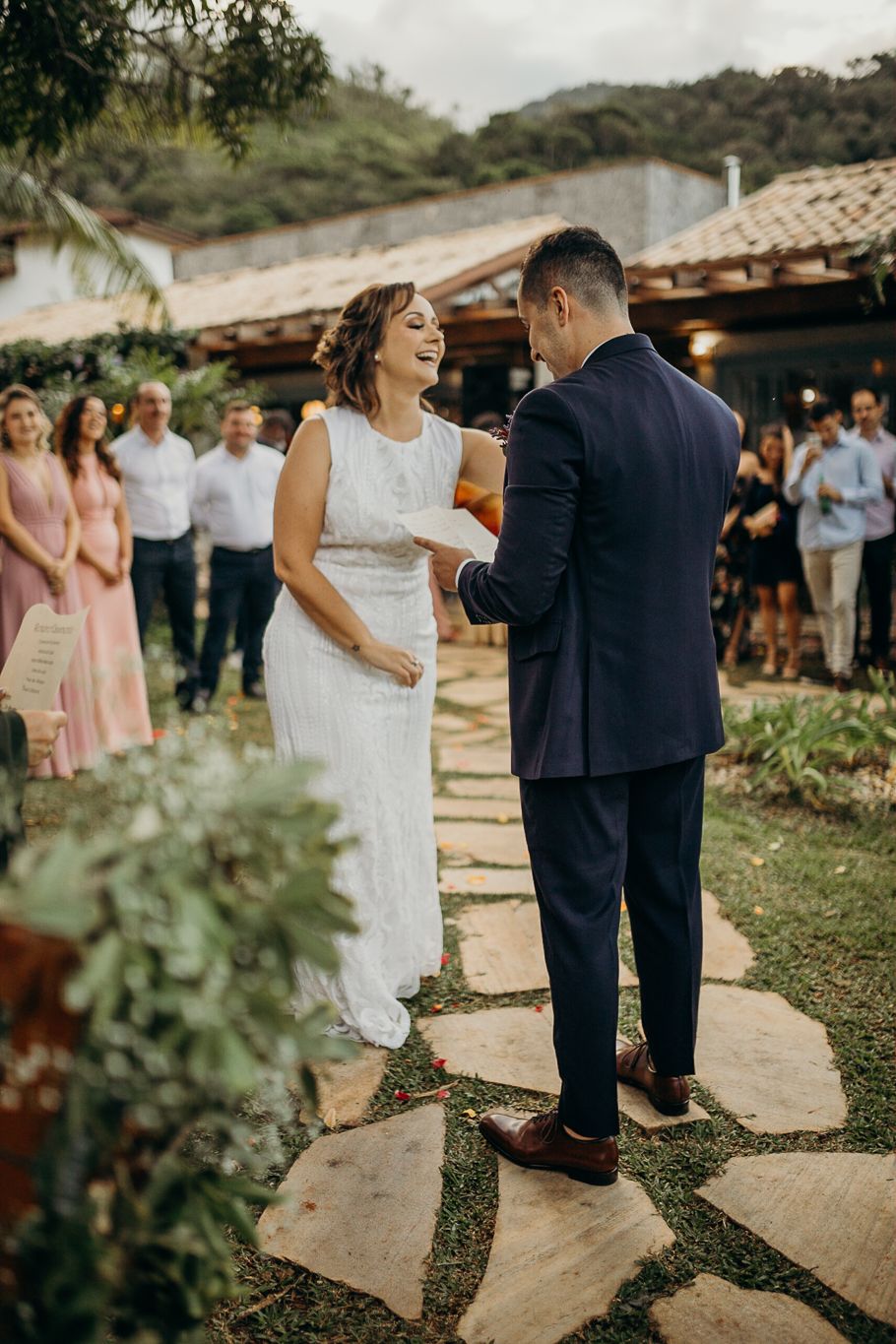 A couple shares a joyful moment during their wedding ceremony on a stone pathway.