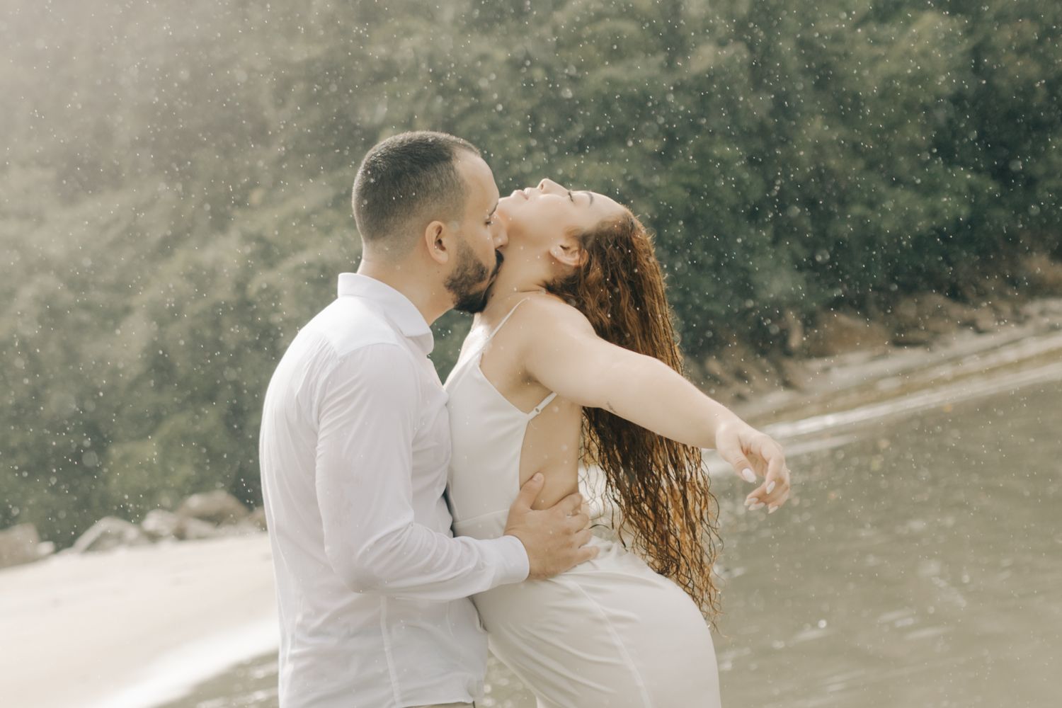 A romantic beachside moment captured as a couple shares a passionate kiss.