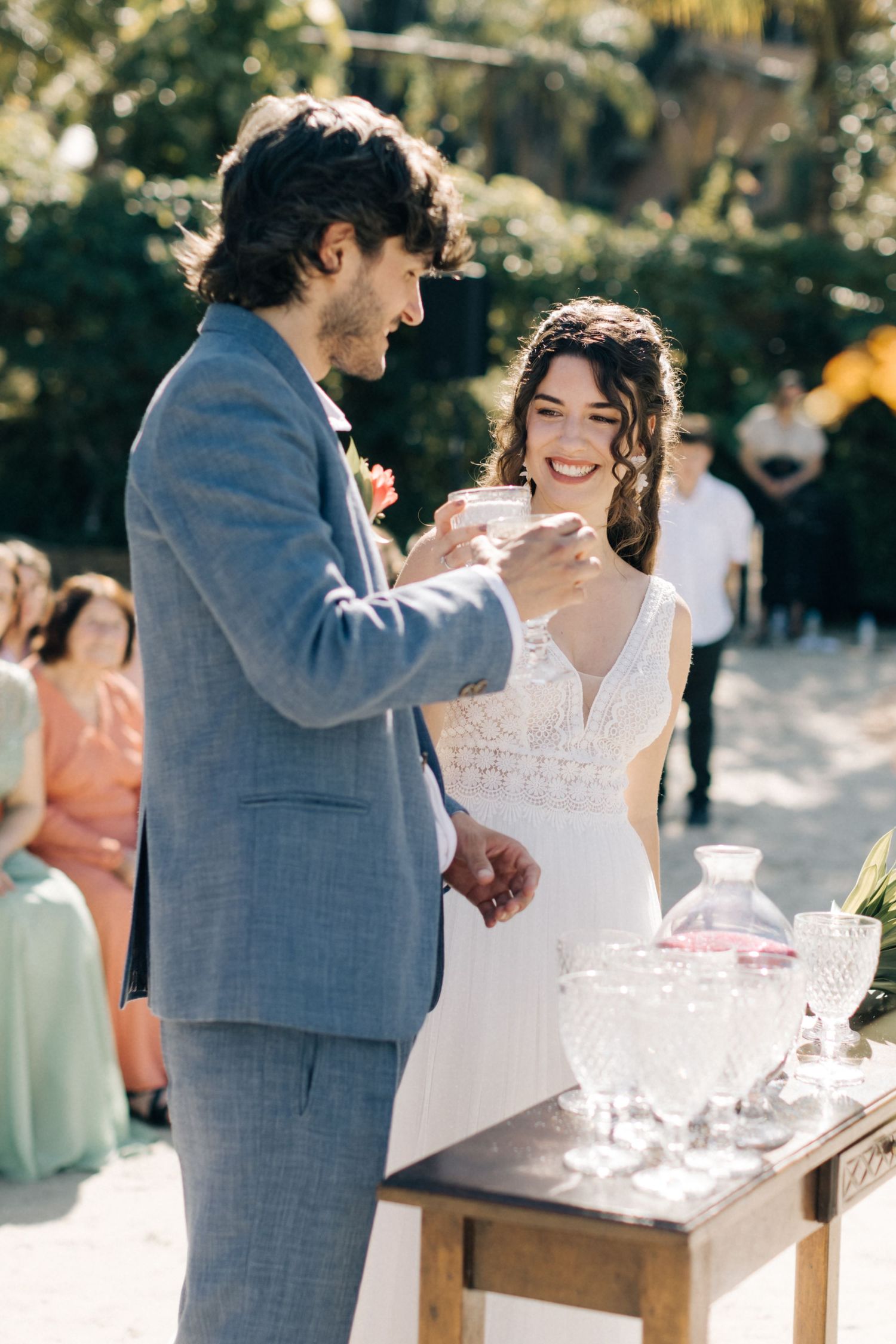 Couple interacts playfully at their wedding drink station decorated with floral arrangements.