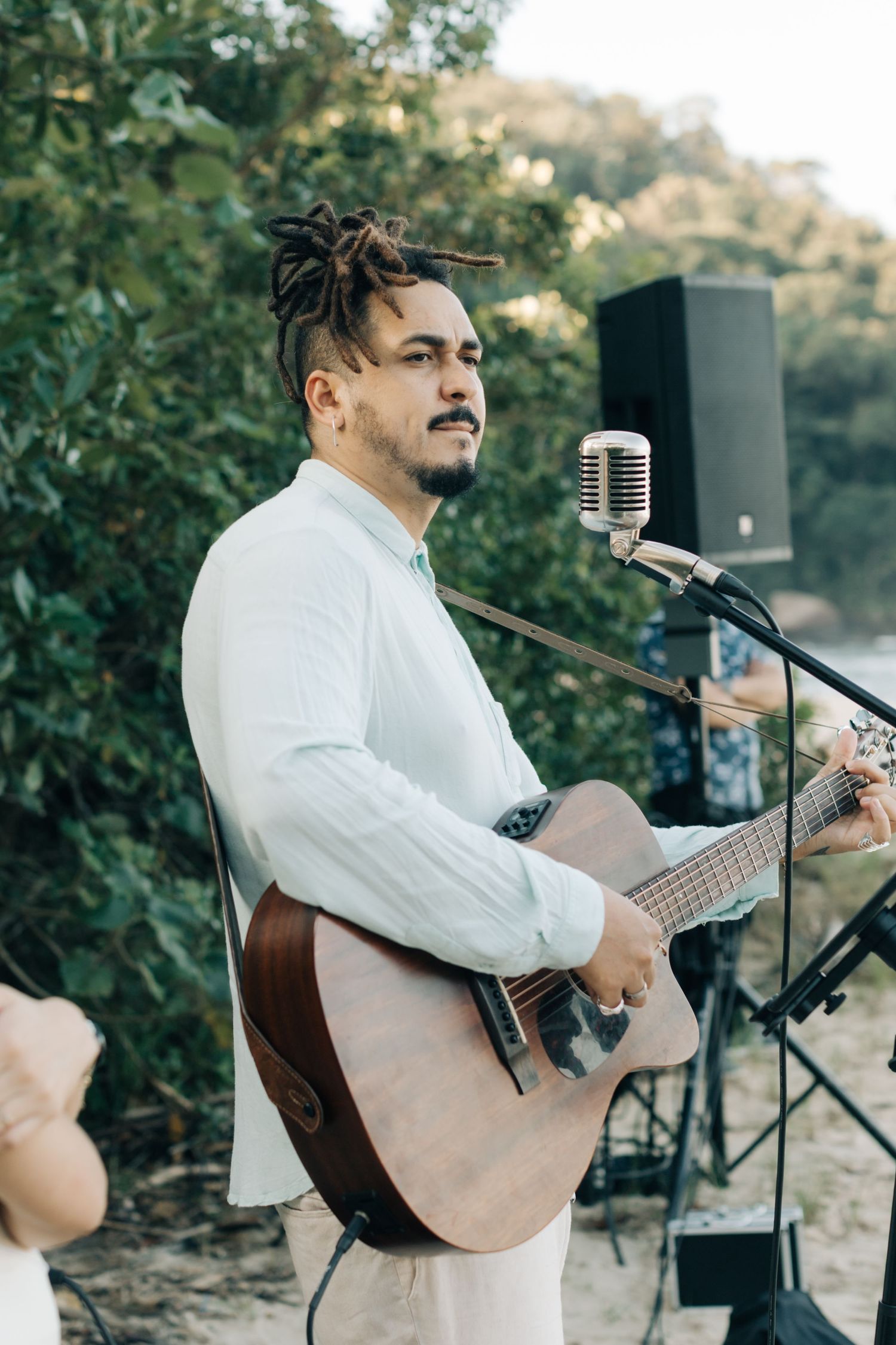 A musician performs with an acoustic guitar and vintage microphone at an outdoor event.