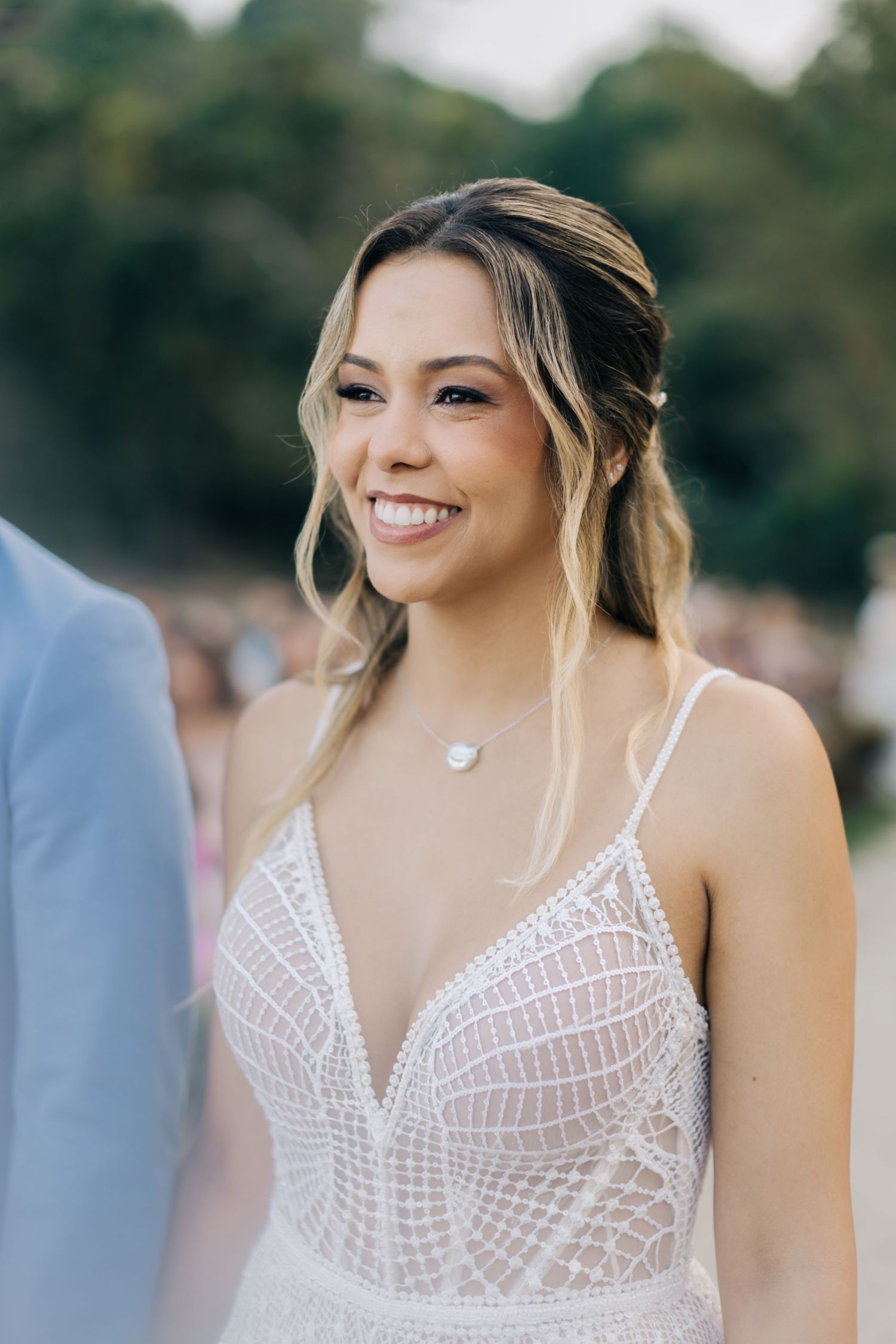Close-up shot of a bride wearing an intricate white lace wedding dress with spaghetti straps.