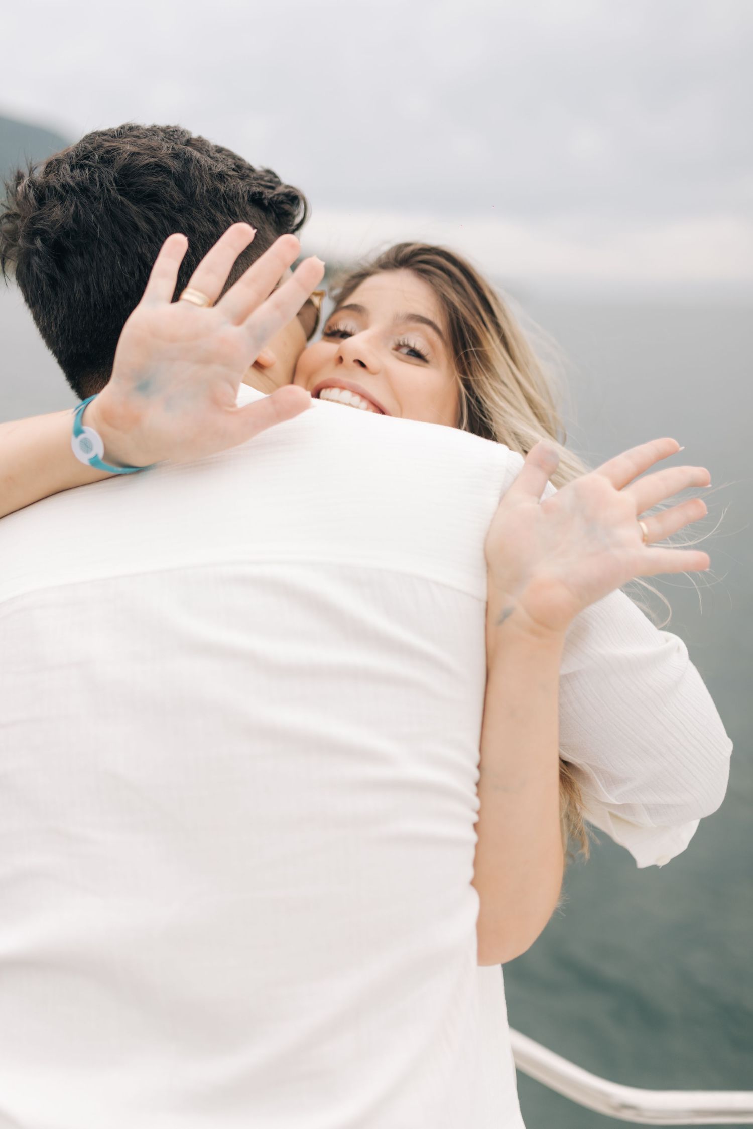 Intimate embrace on boat deck with ocean backdrop.