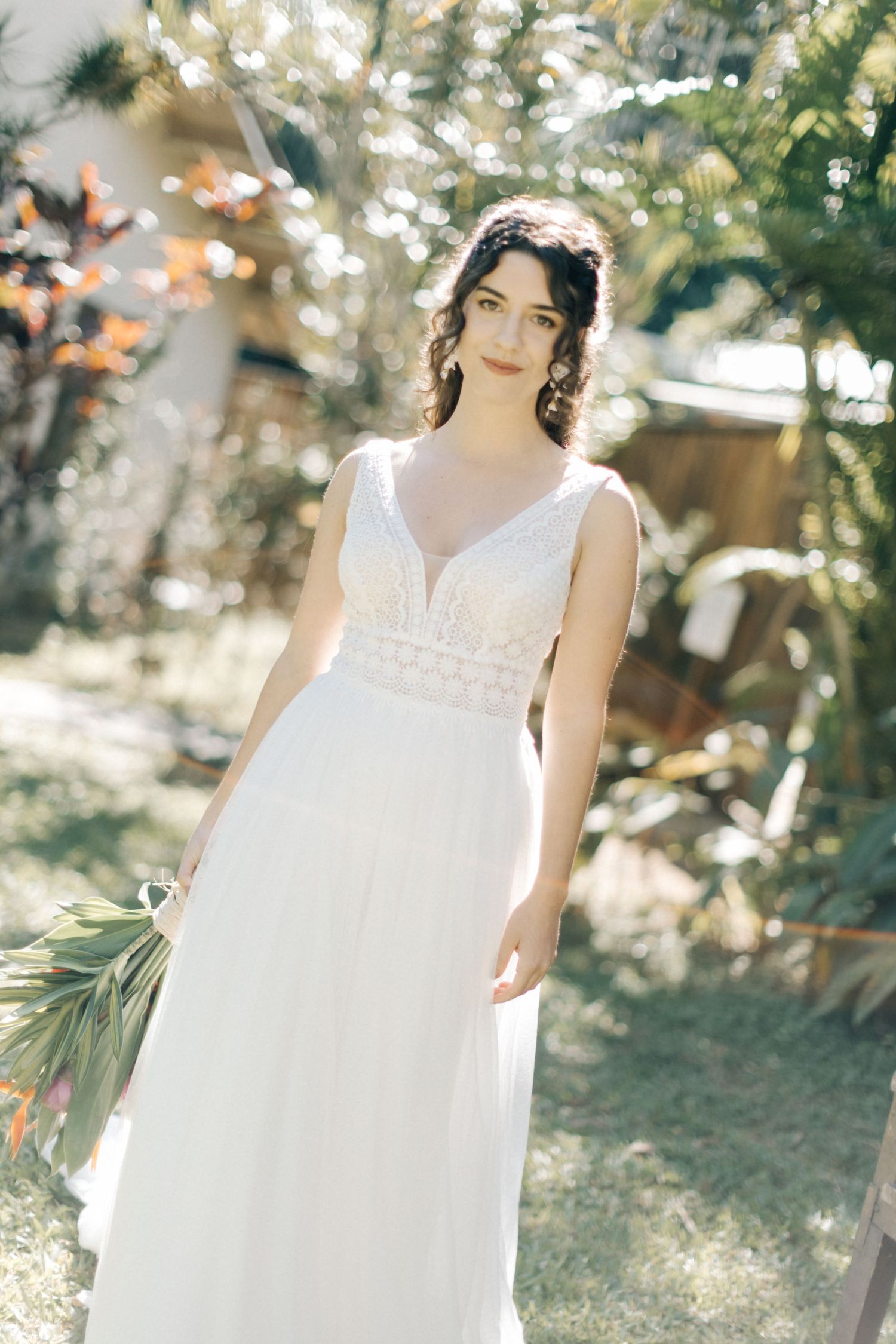A romantic bridal portrait in a garden setting featuring an elegant white wedding dress with delicate lace details.