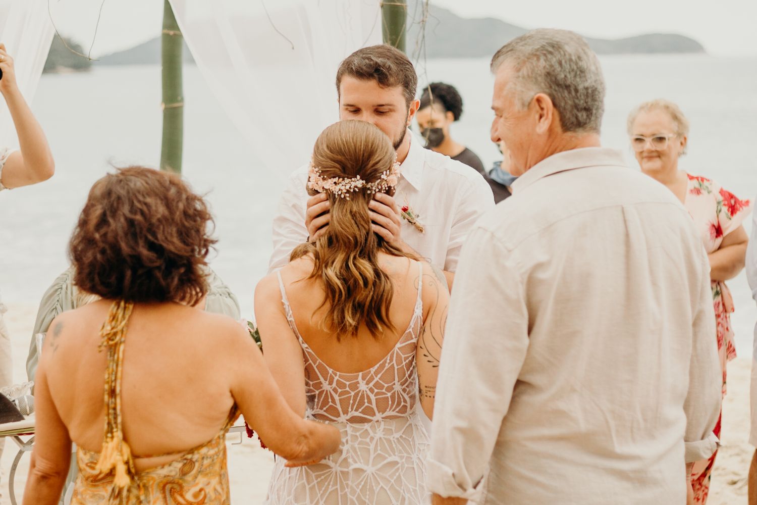 Intimate moment during a beach wedding ceremony under white canopy.
