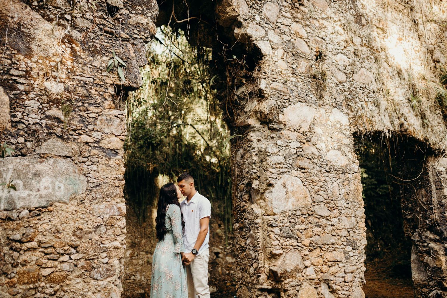 A romantic moment captured in a stone archway of historic ruins with natural lighting.