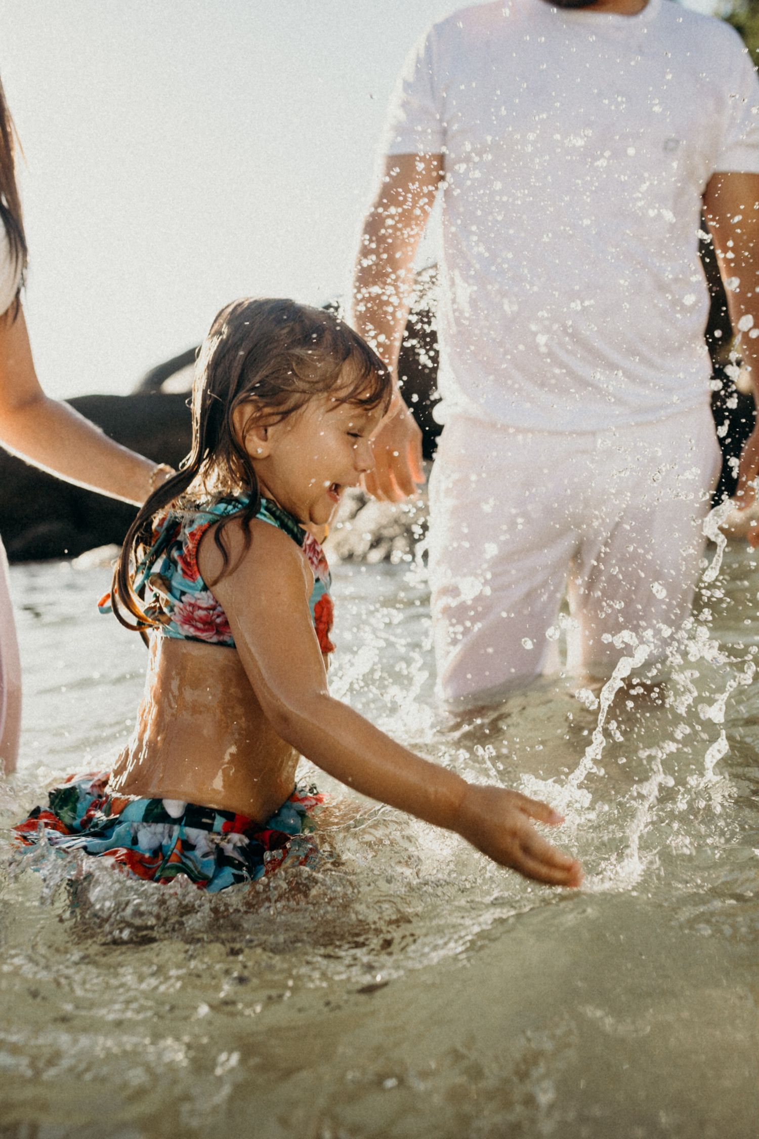 Close-up of children playing and splashing in crystal clear beach water.