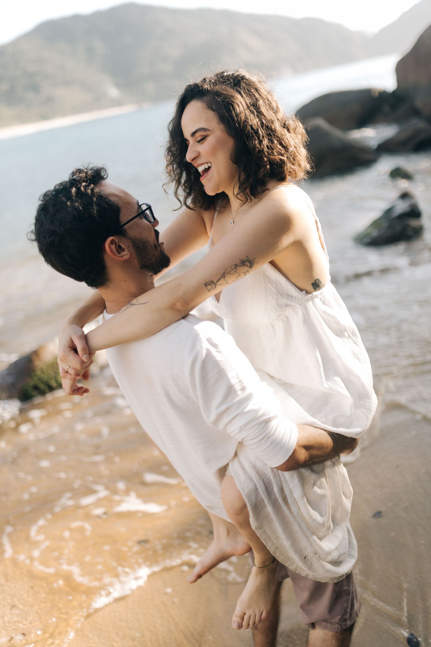 Joyful couple playing and laughing together on a sandy beach.