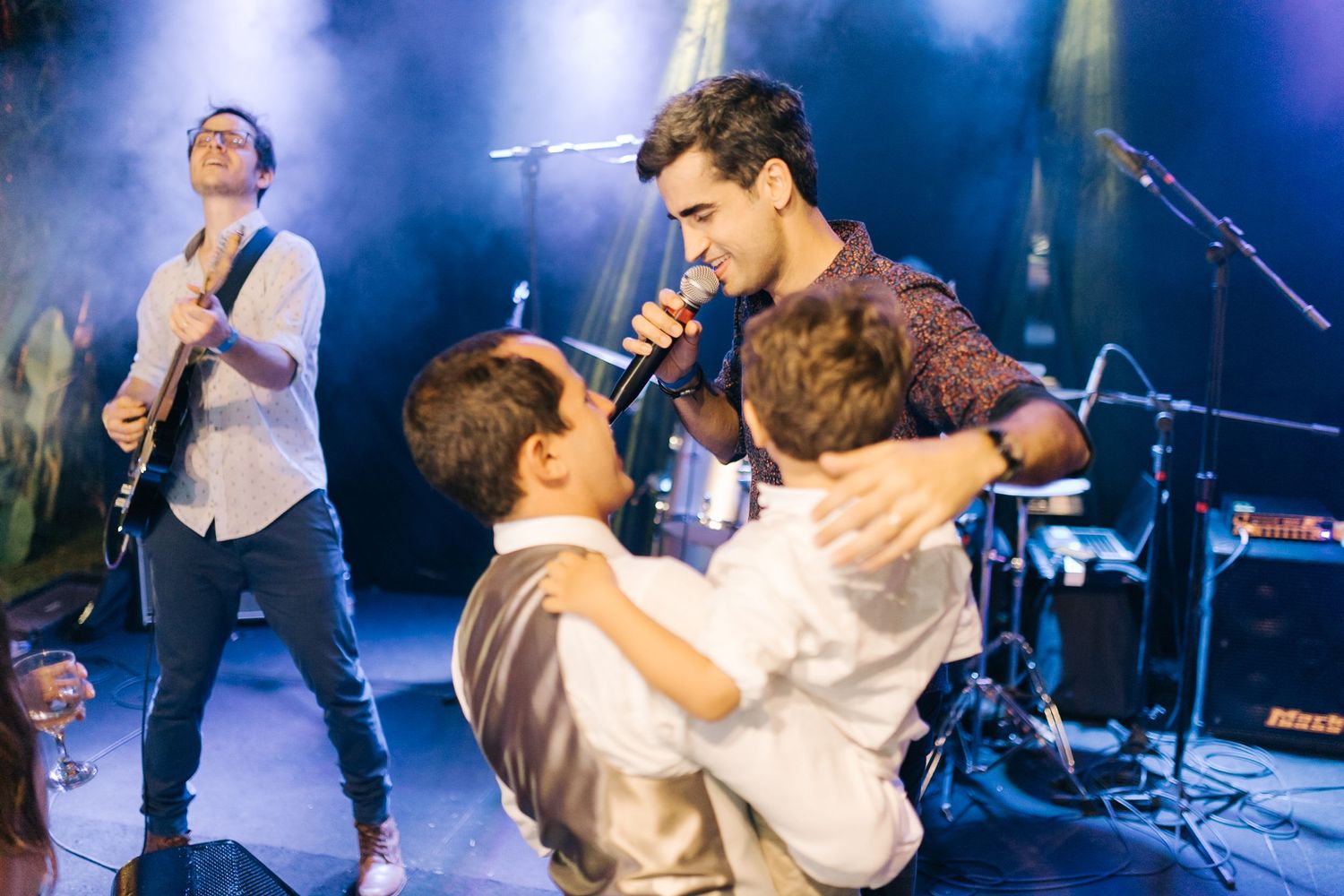 Live band performing on stage with blue stage lighting at an evening event.