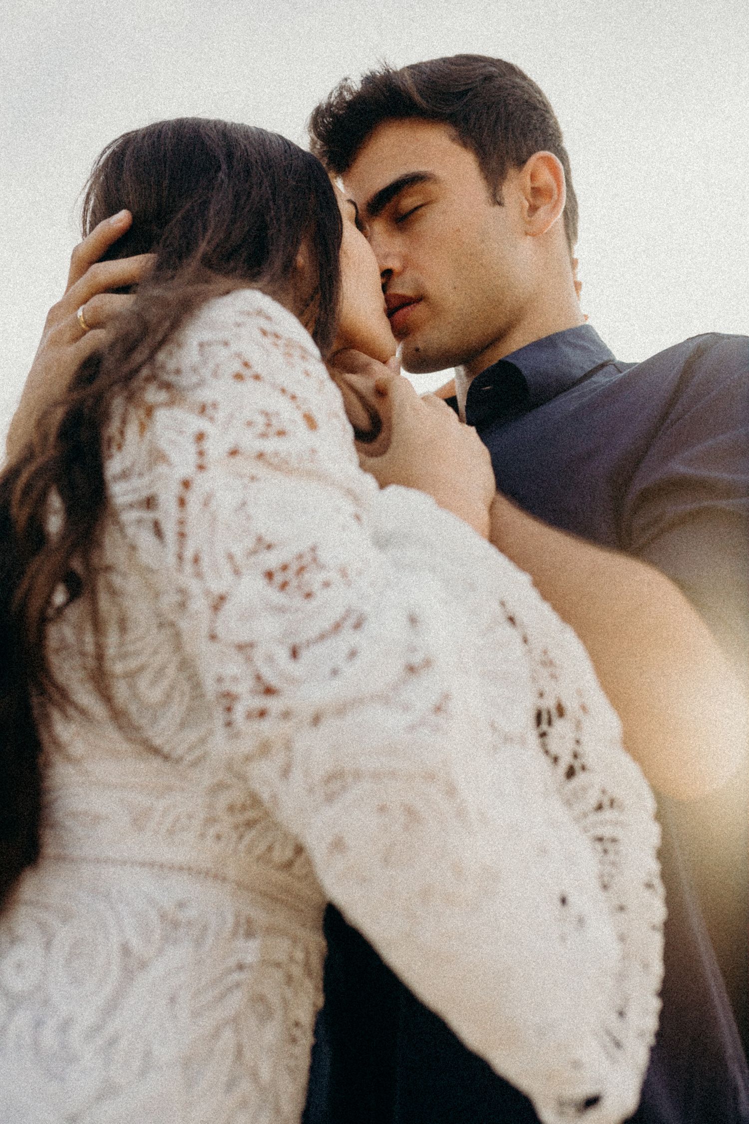 Sun-kissed portraits of a couple in white lace and dark clothing sharing tender moments.