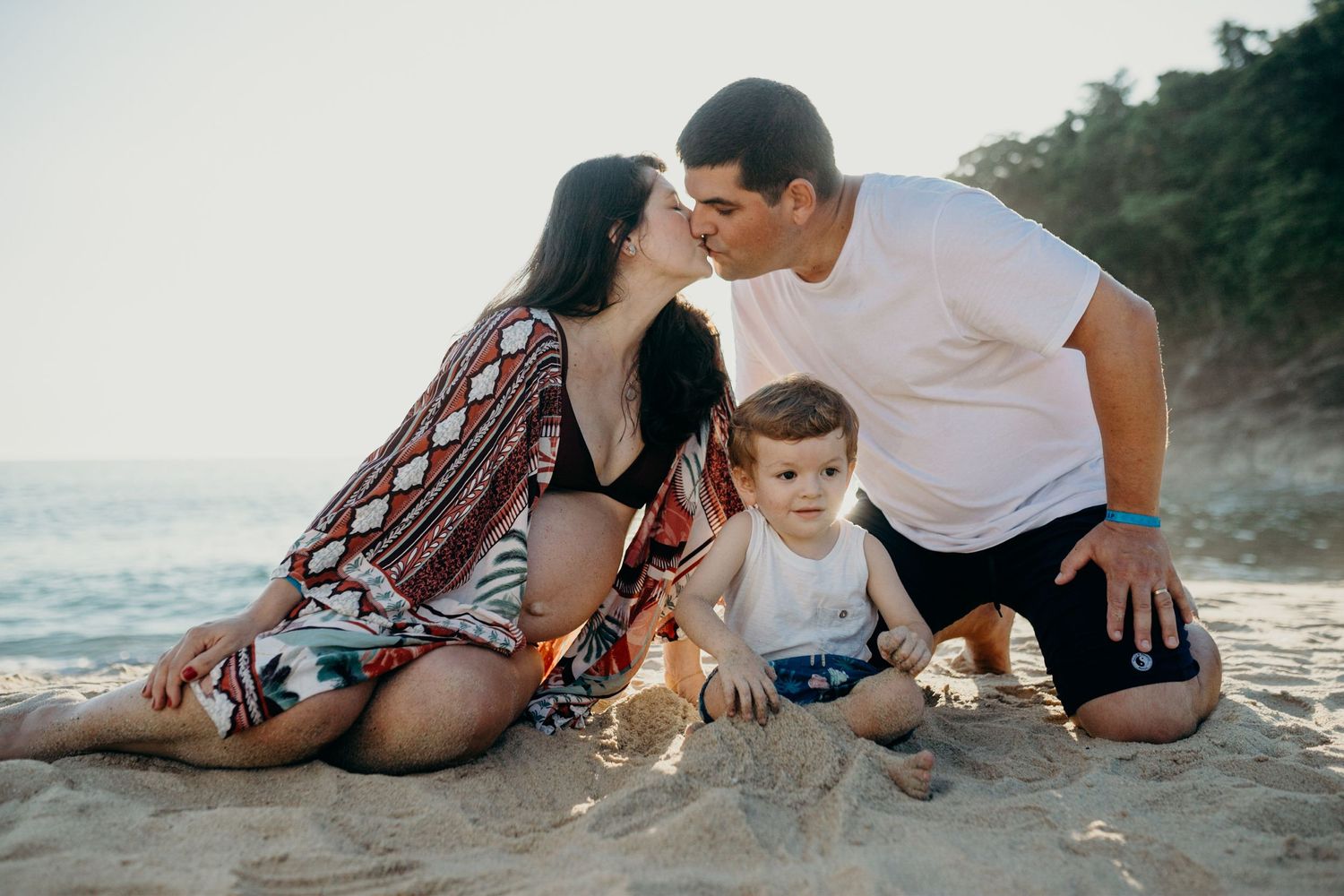Family enjoying peaceful moment together on sandy beach at sunset.
